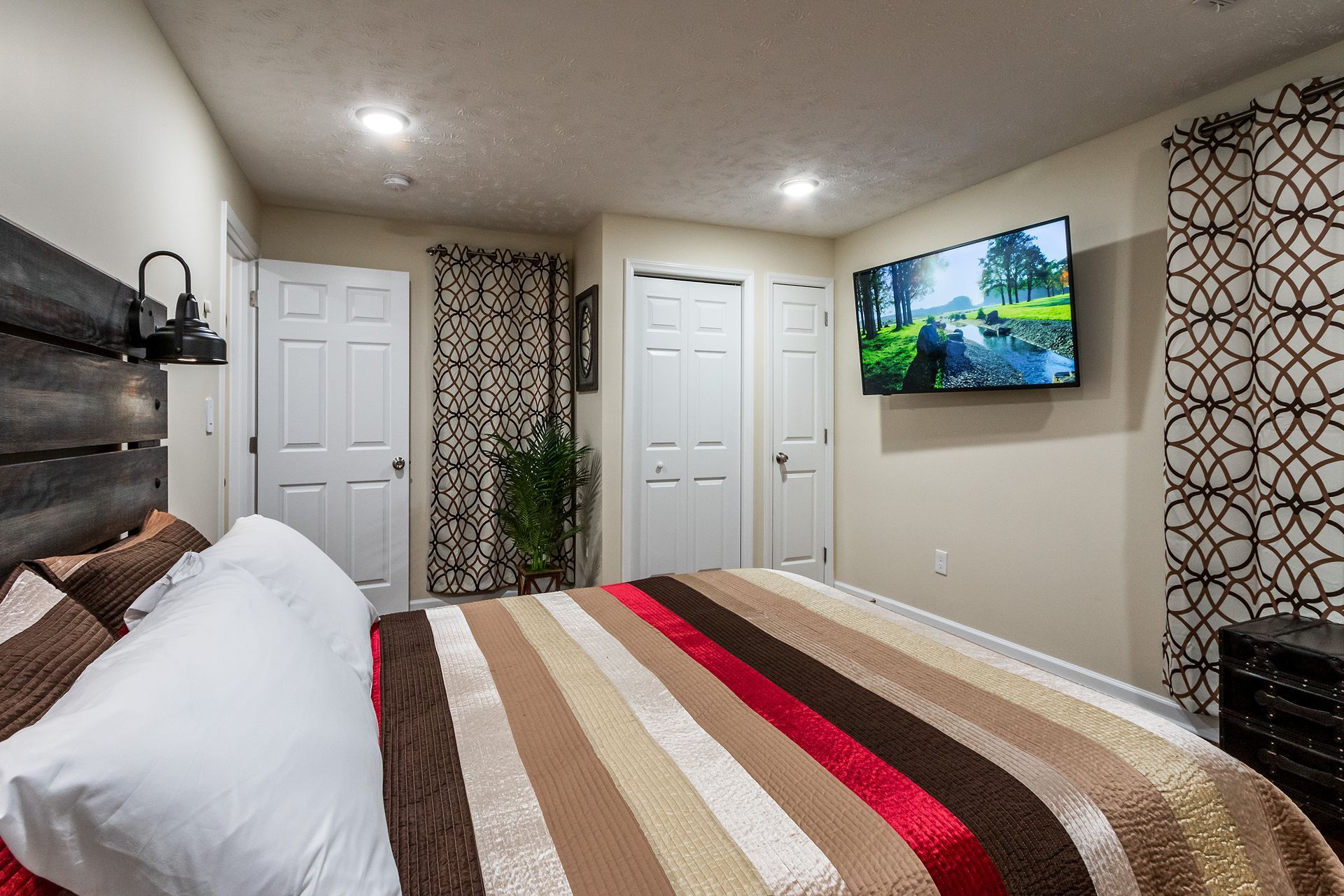A bedroom with a bed and a flat screen tv on the wall.