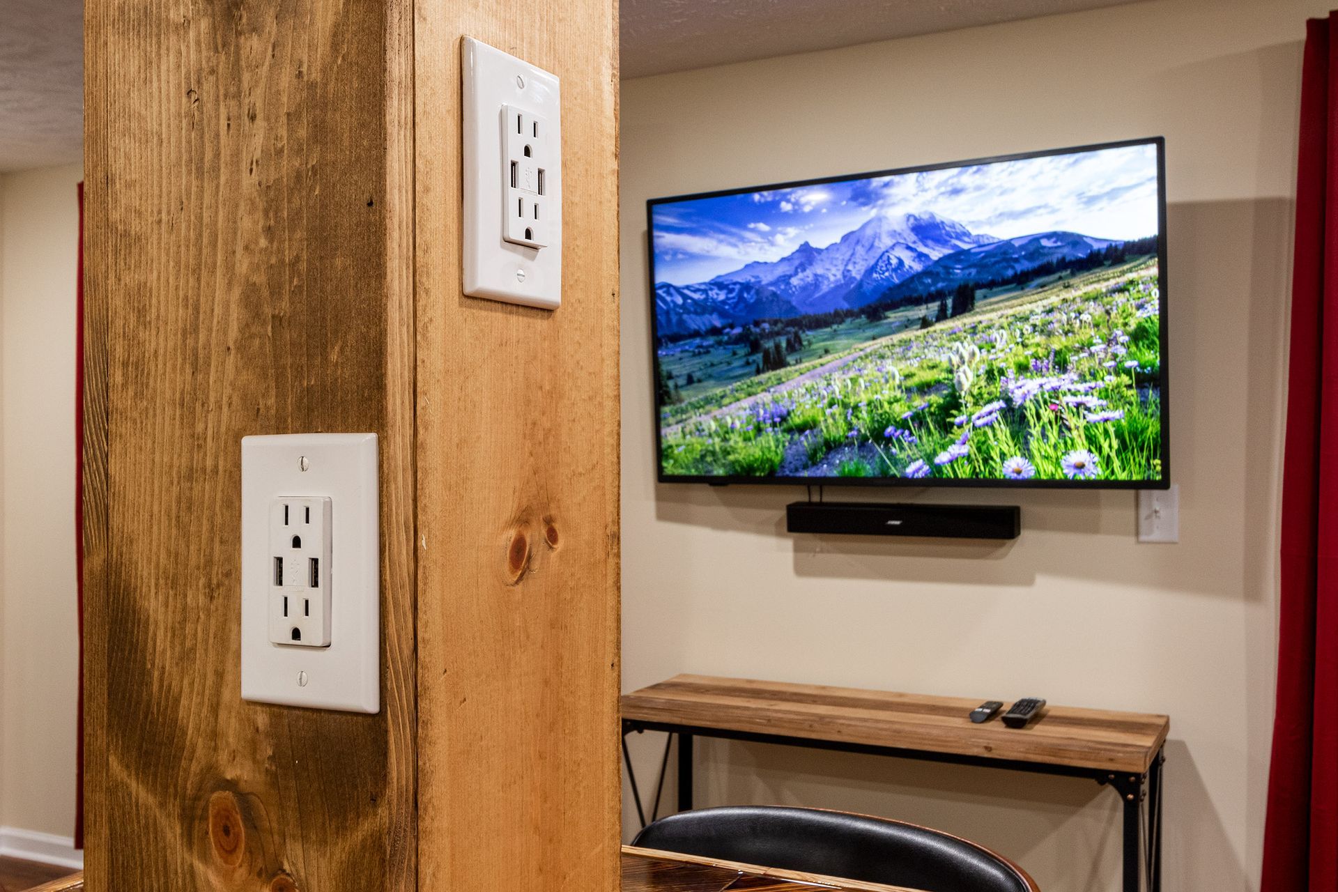 A flat screen tv is hanging on a wall next to a wooden pillar.