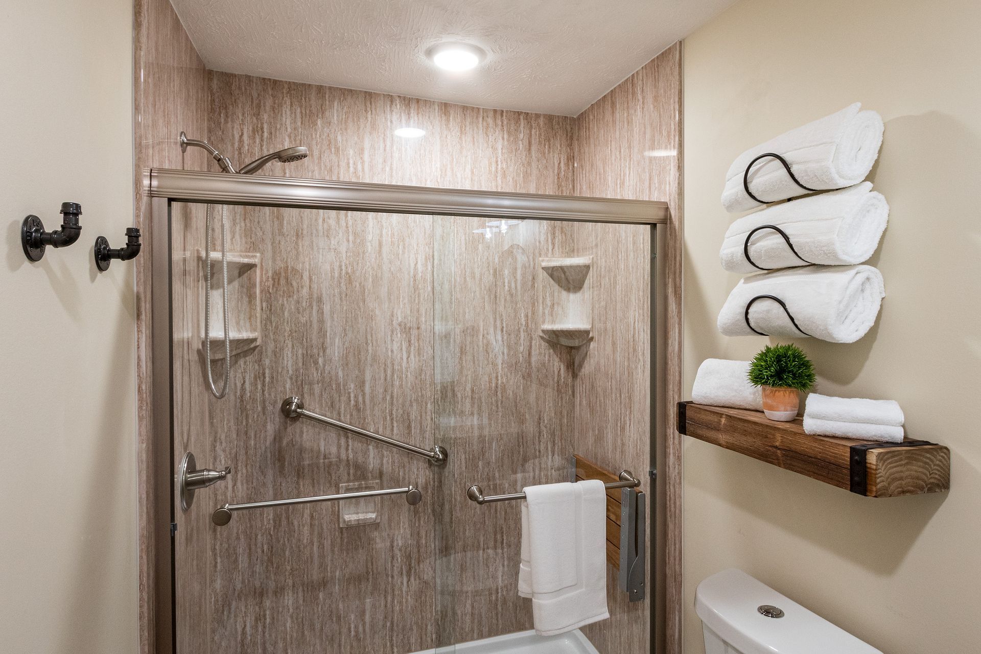A bathroom with a toilet , shower , and towels.