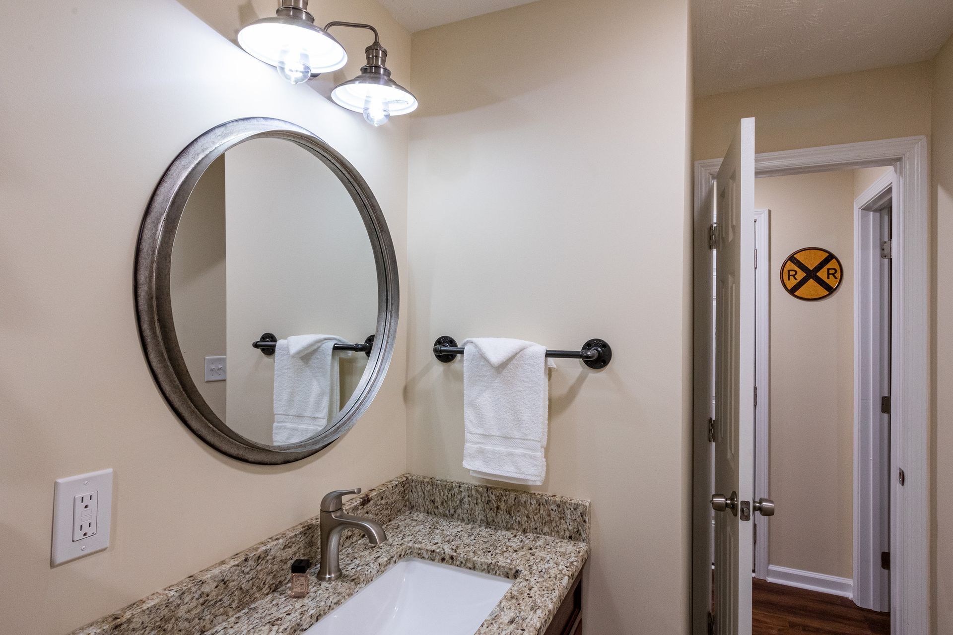A bathroom with a sink , mirror and towel rack.