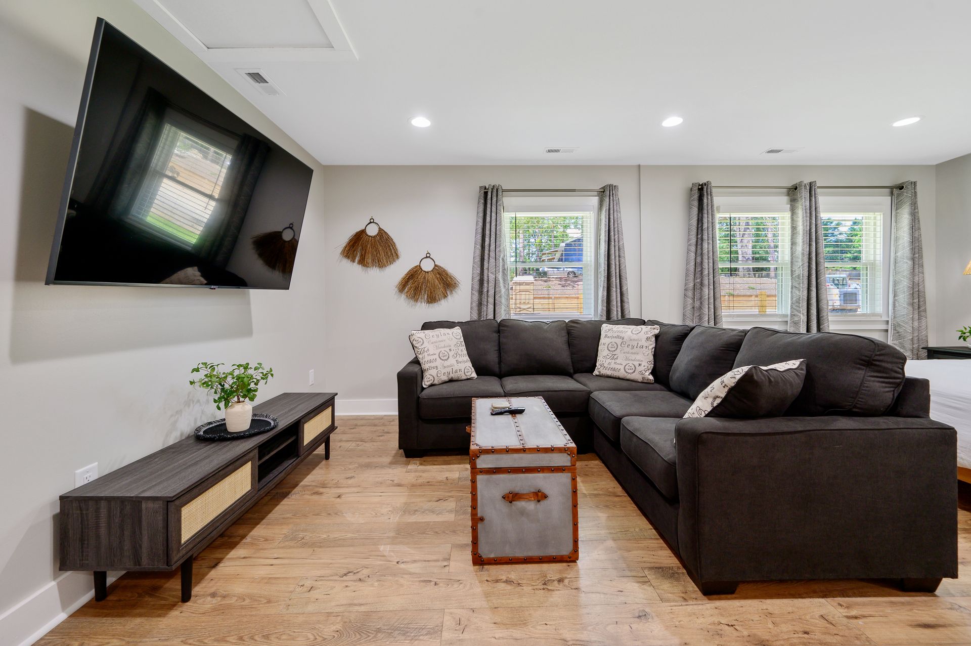 A living room with a large sectional couch and a flat screen tv on the wall.
