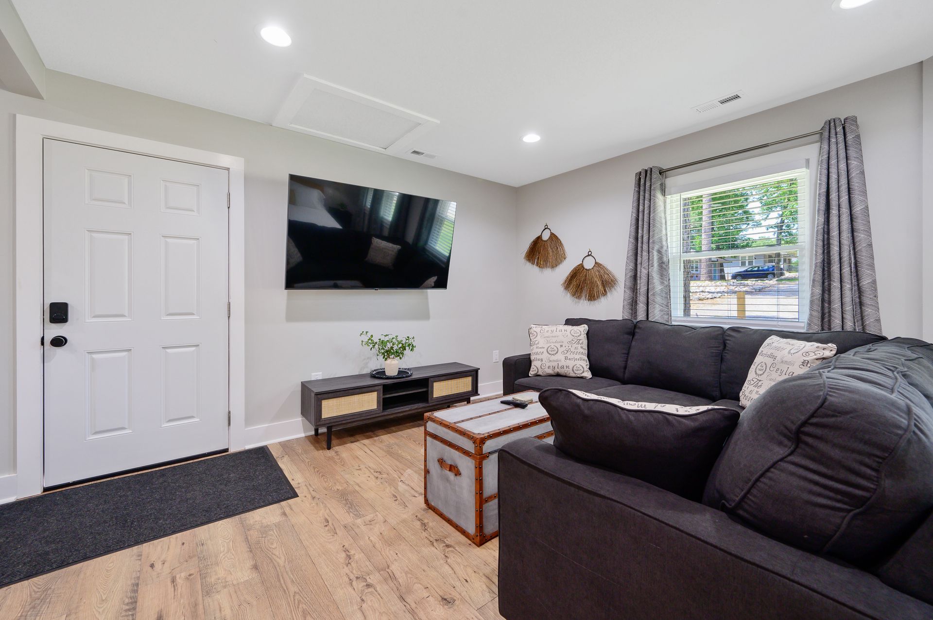 A living room with a couch and a flat screen tv on the wall.