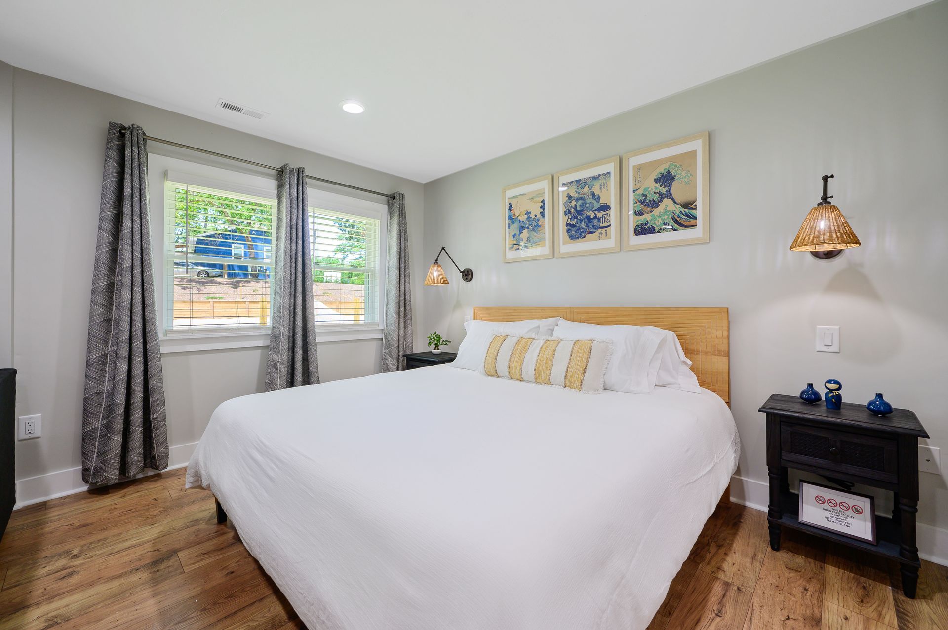 A bedroom with a king size bed , nightstand , and two windows.