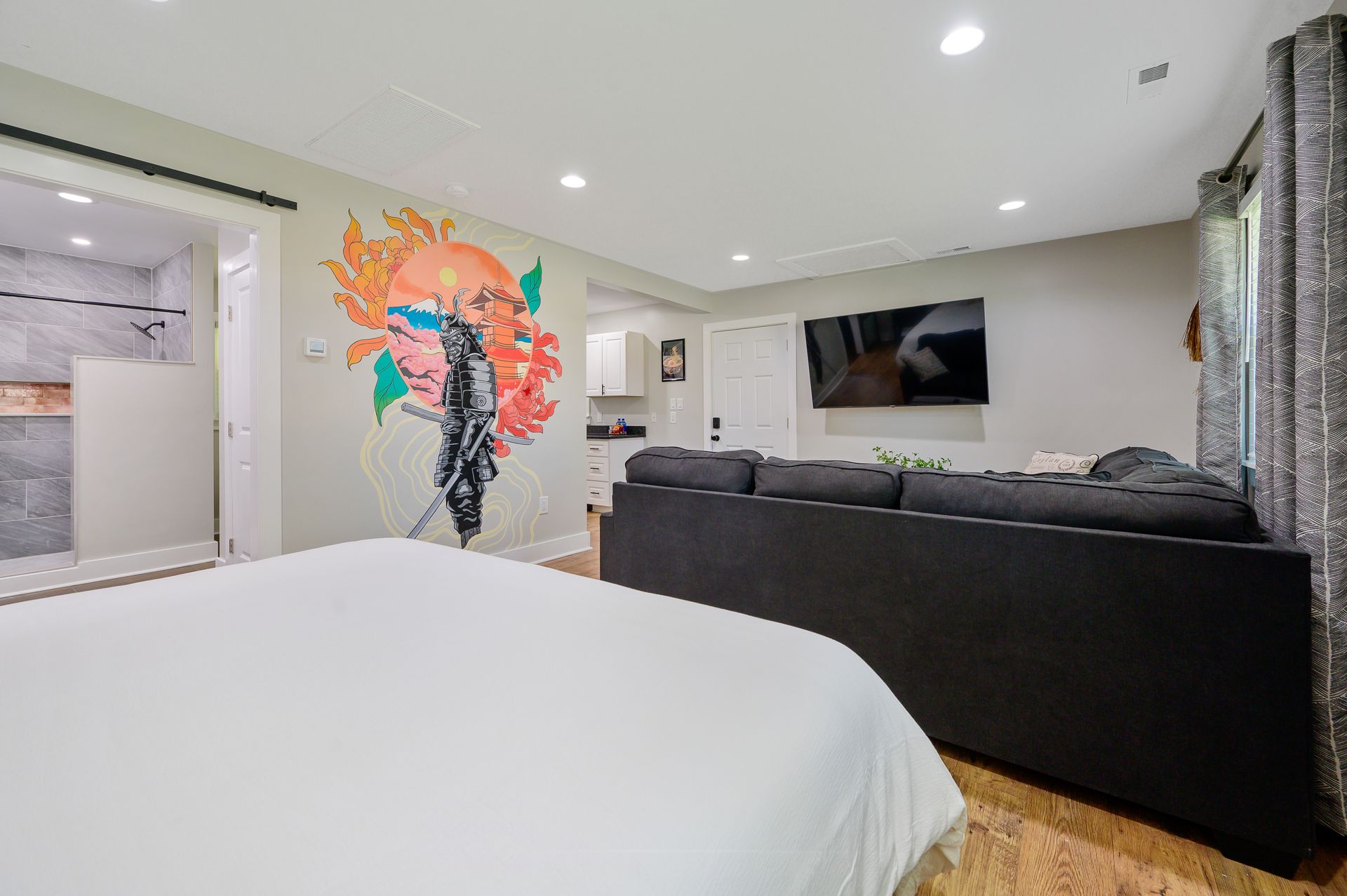 A bedroom with a bed , couch , television and a mural on the wall.