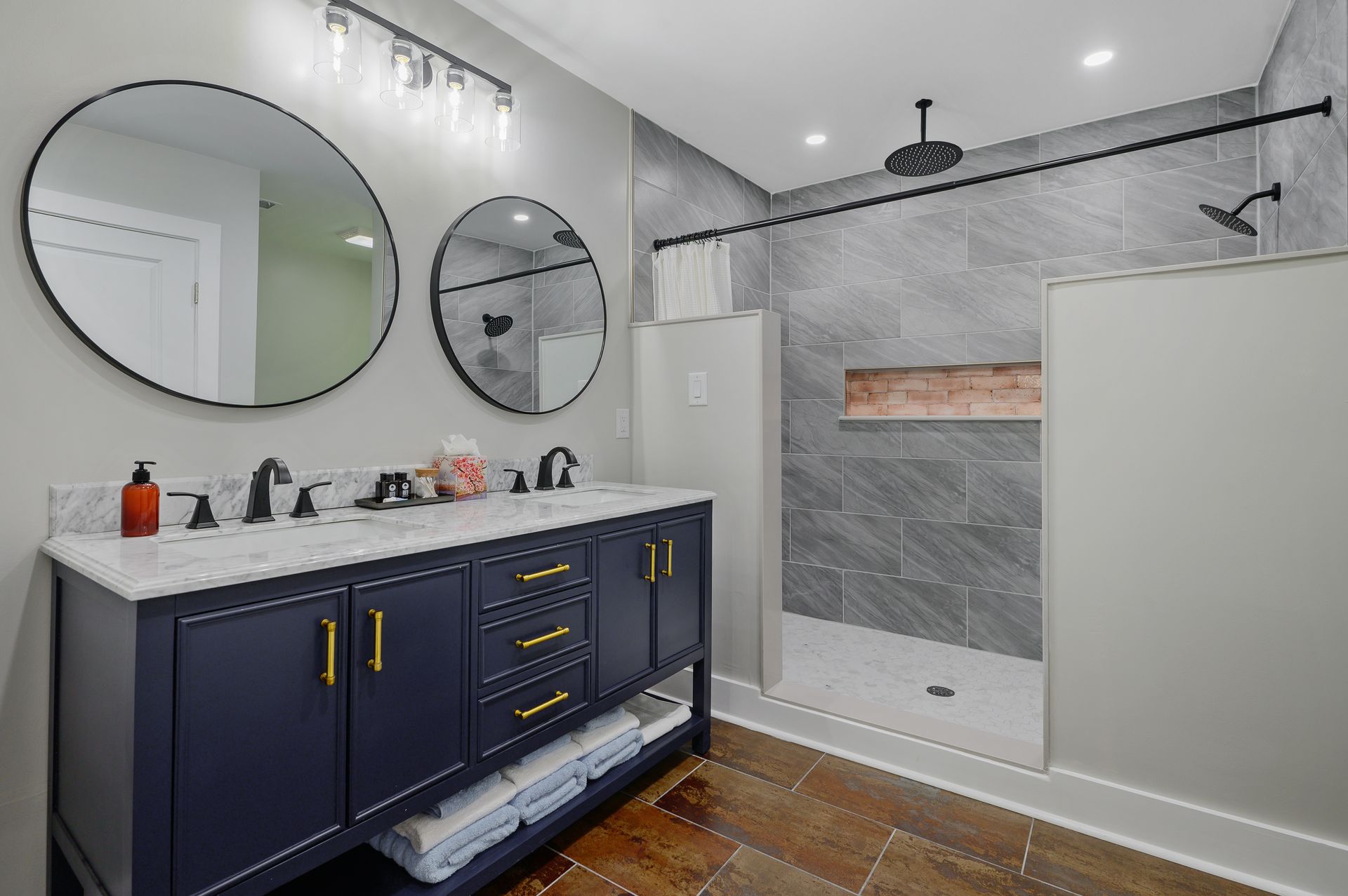 A bathroom with two sinks , two mirrors and a walk in shower.