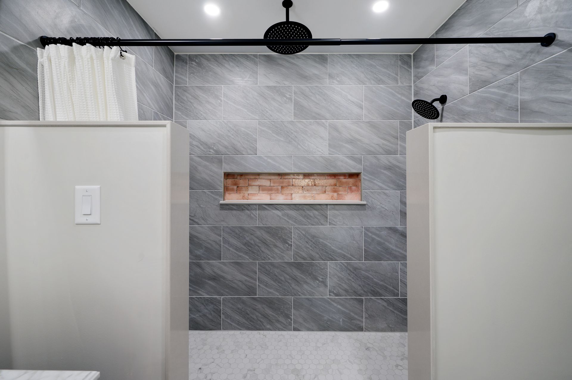 A bathroom with two shower stalls and a shower head.