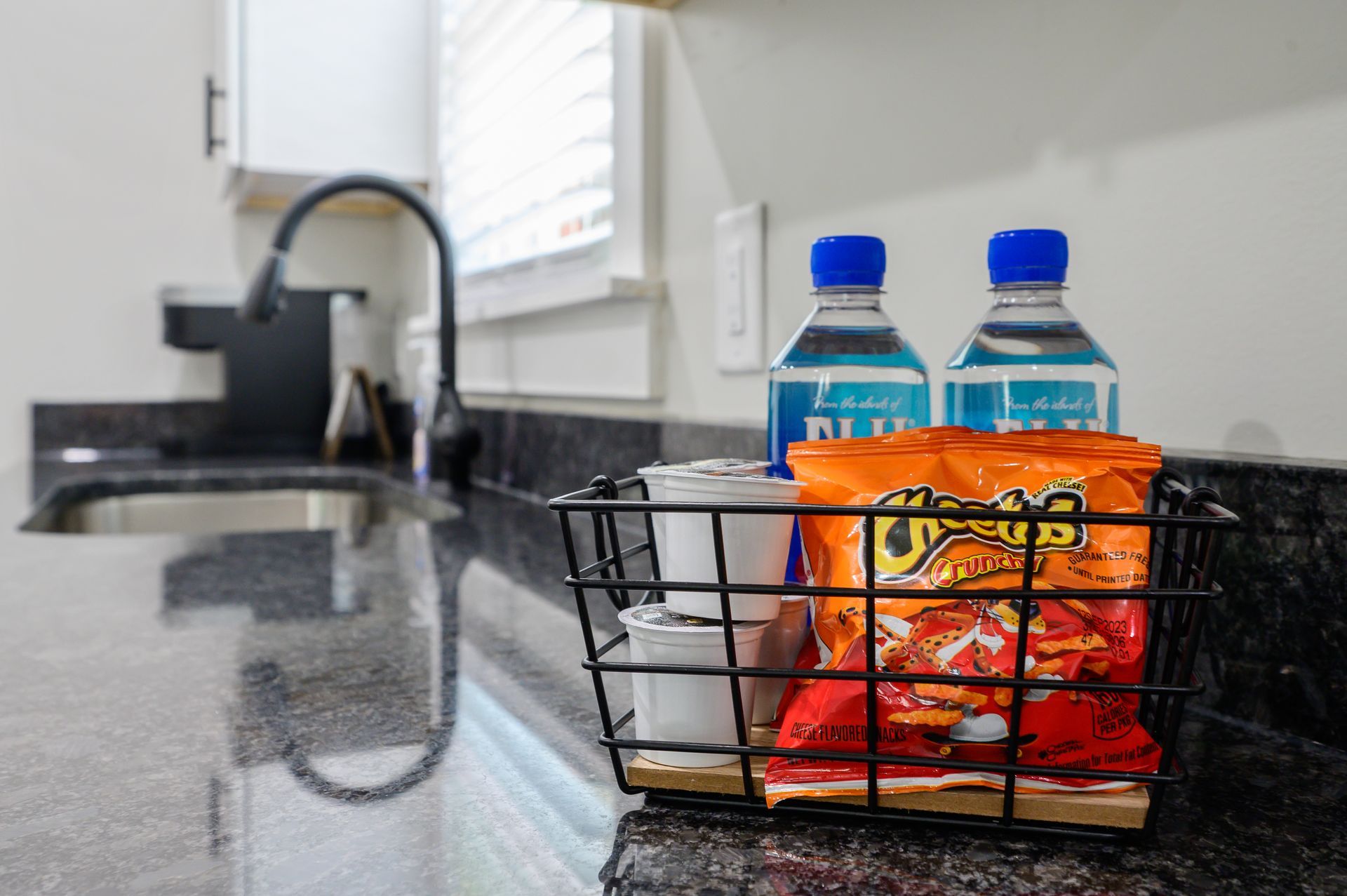 A basket filled with chips and water bottles on a kitchen counter.