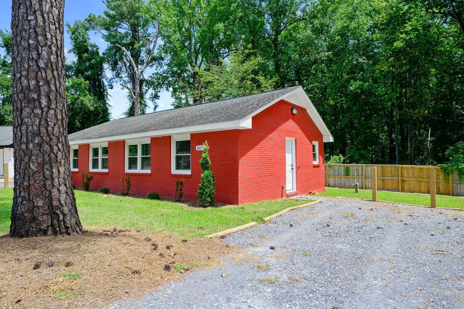 A red house with a gravel driveway in front of it