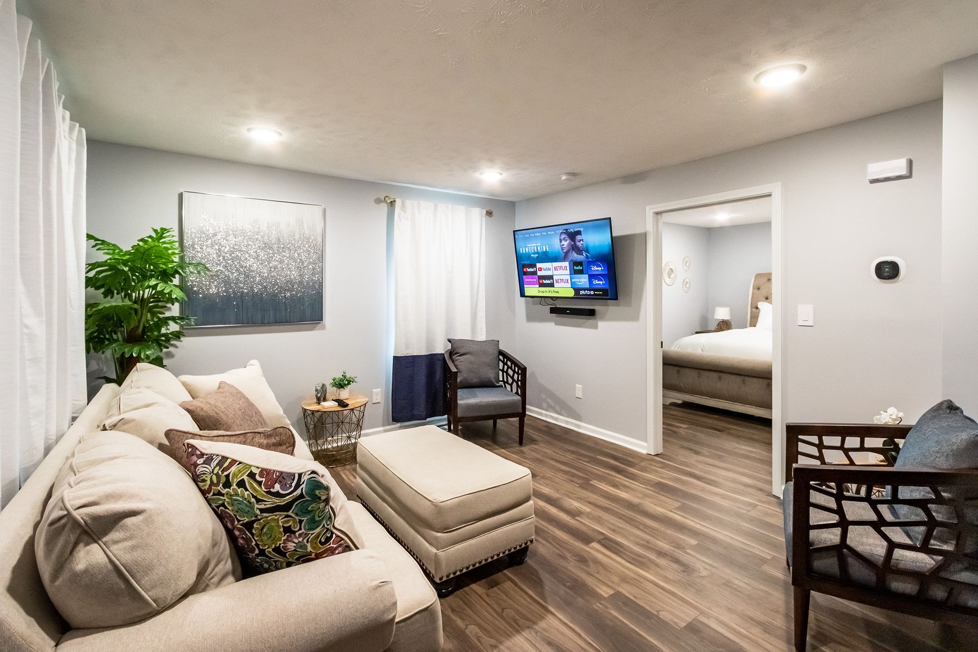 A living room with a couch , chairs , ottoman and television.