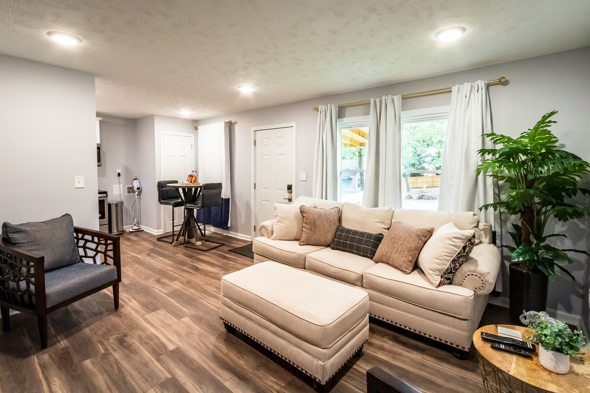 A living room with a couch , chair , ottoman and table.