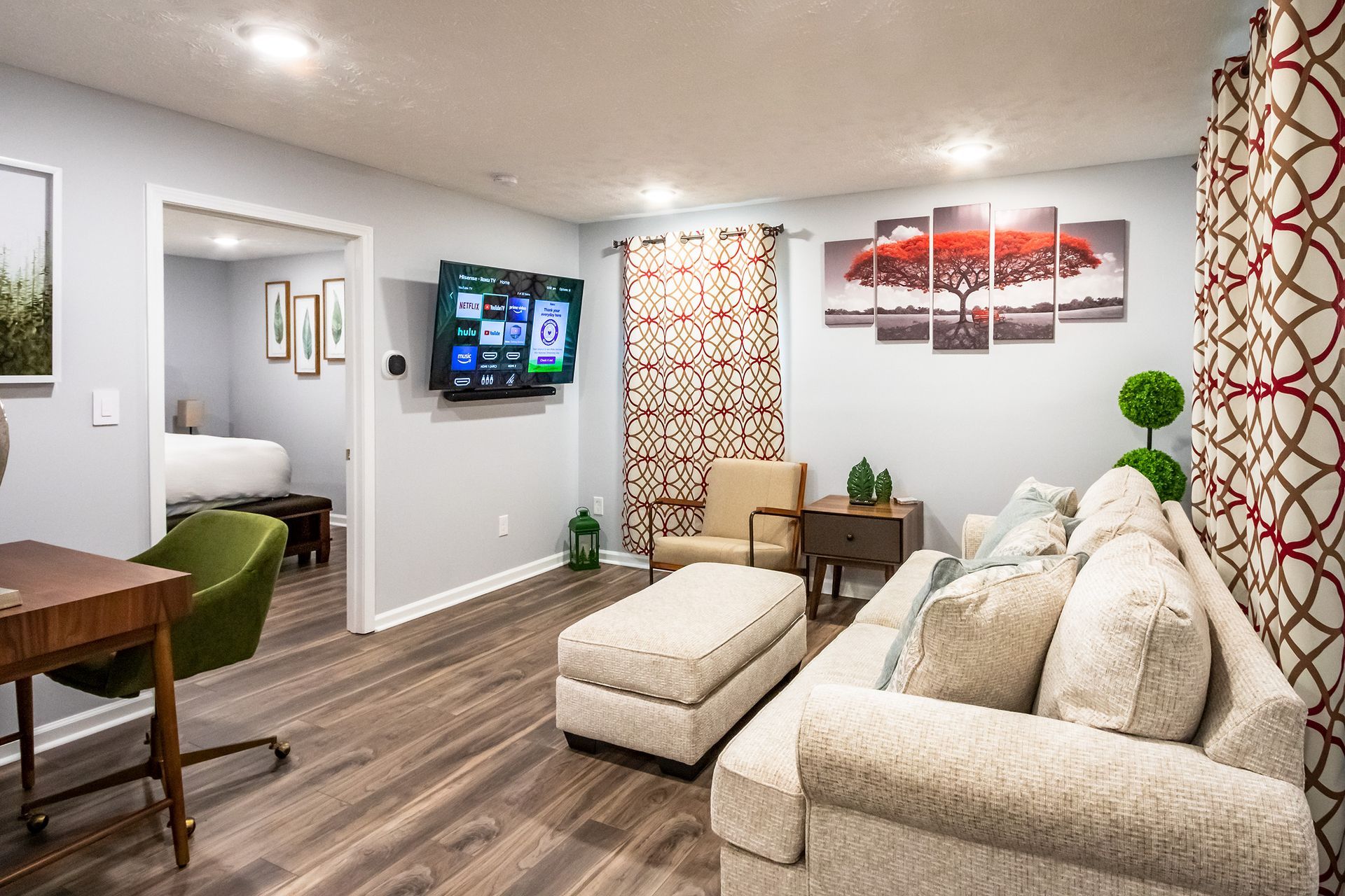 A living room with a couch , chair , desk and television.
