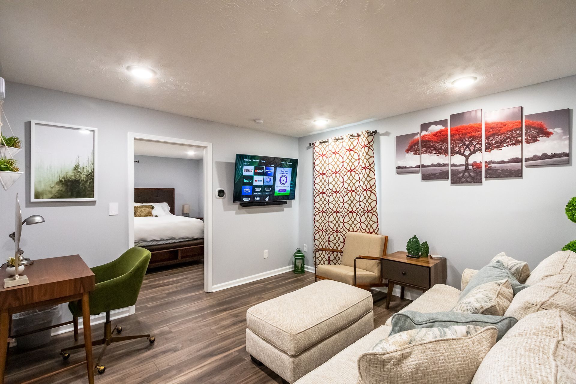 A living room with a couch , chair , desk and television.