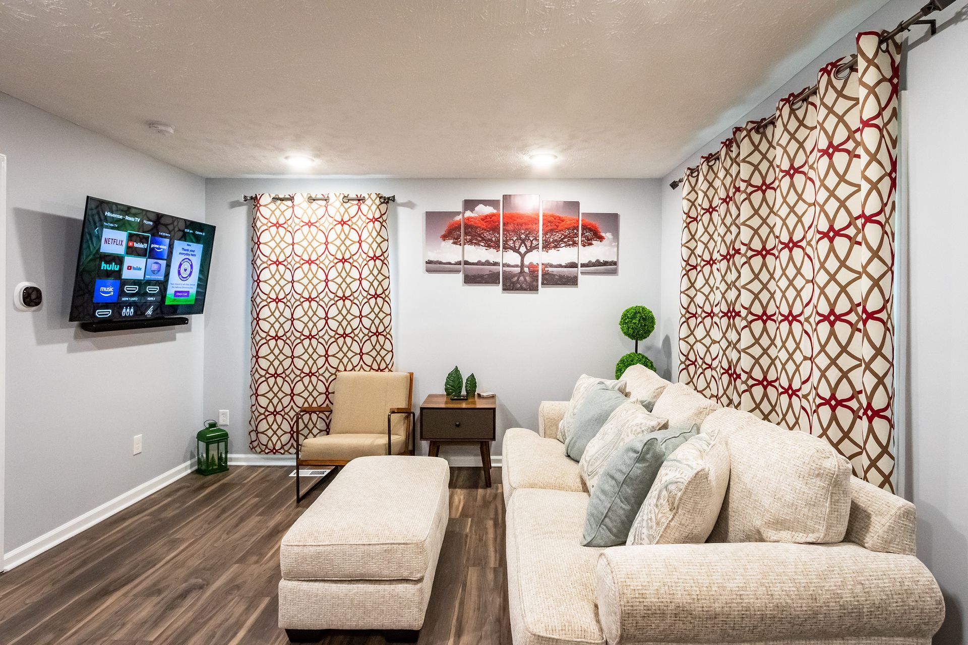 A living room with a couch , chair , ottoman and television.