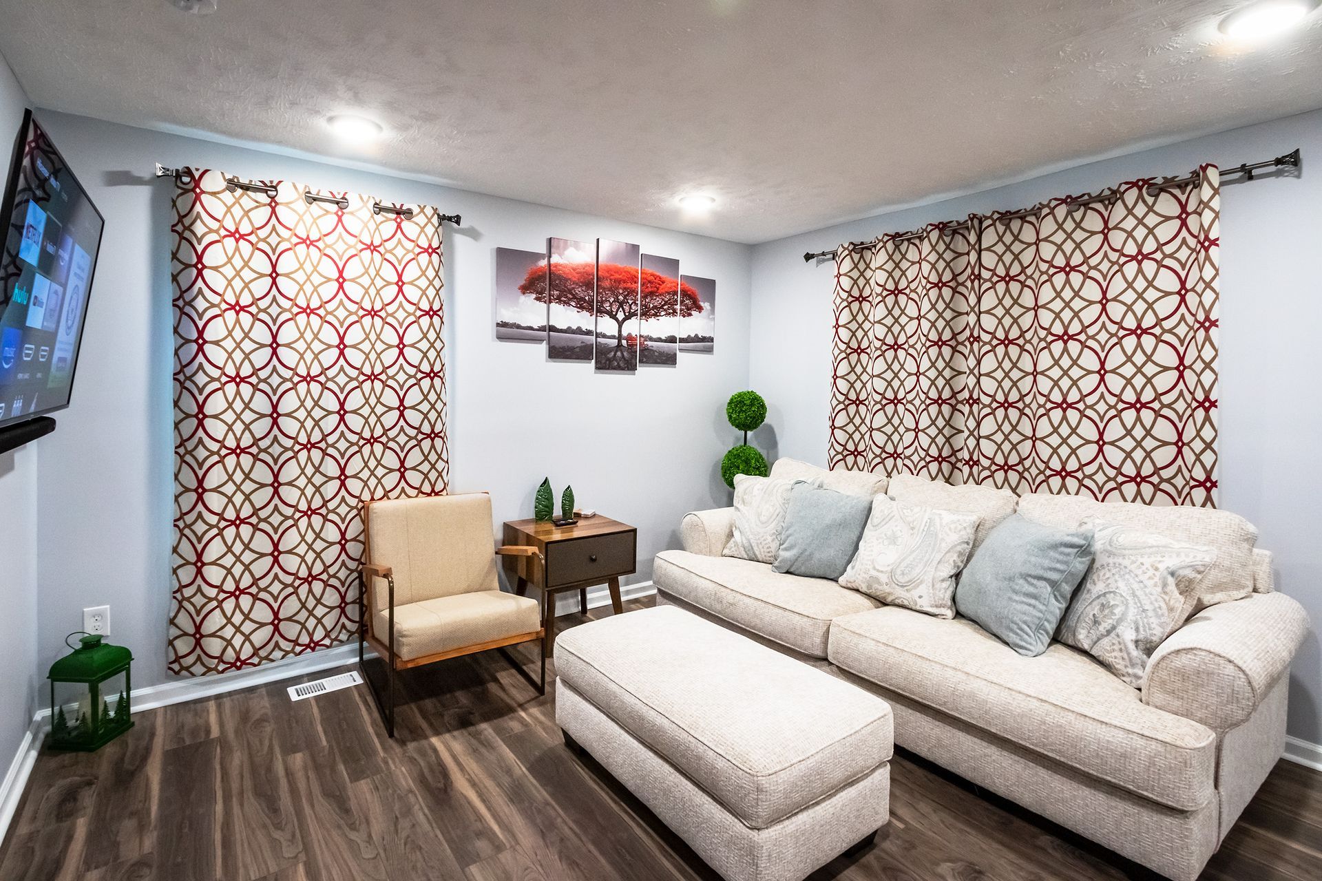 A living room with a couch , chair , ottoman and television.