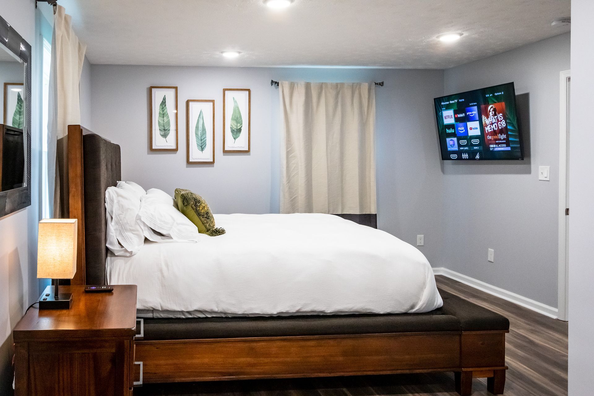 A bedroom with a king size bed and a flat screen tv on the wall.