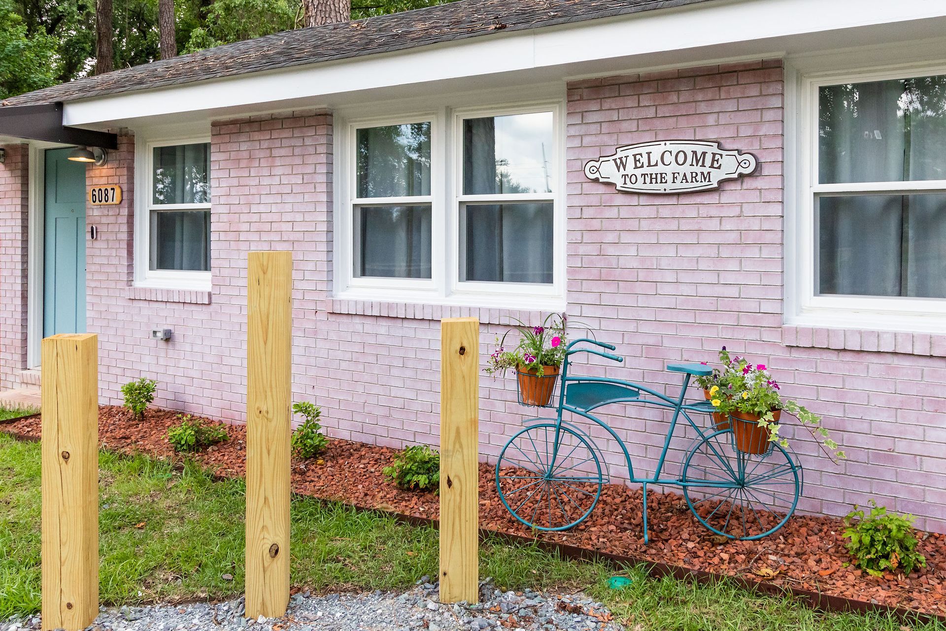 A pink brick house with a blue bicycle in front of it.