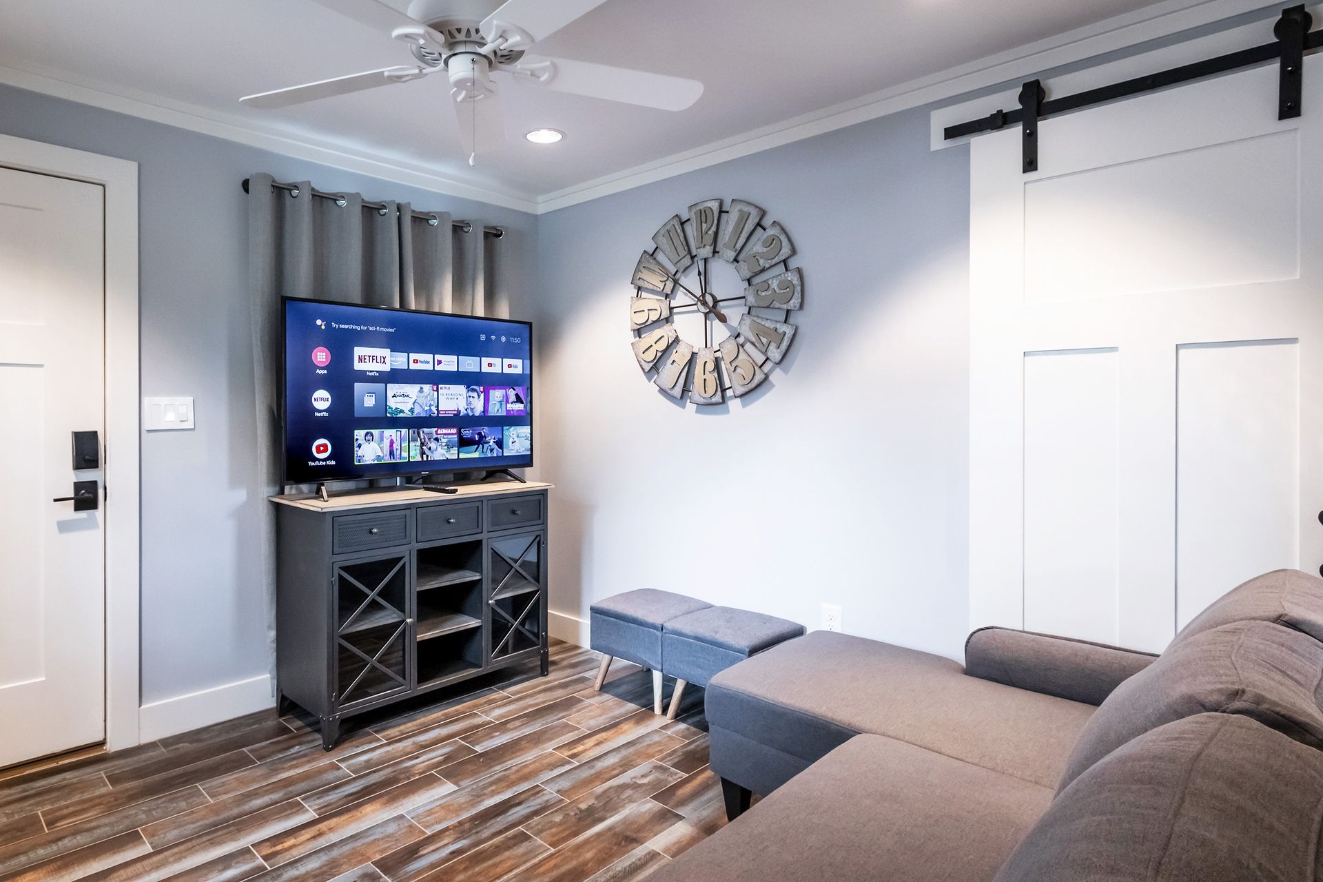 A living room with a couch , television , and ceiling fan.