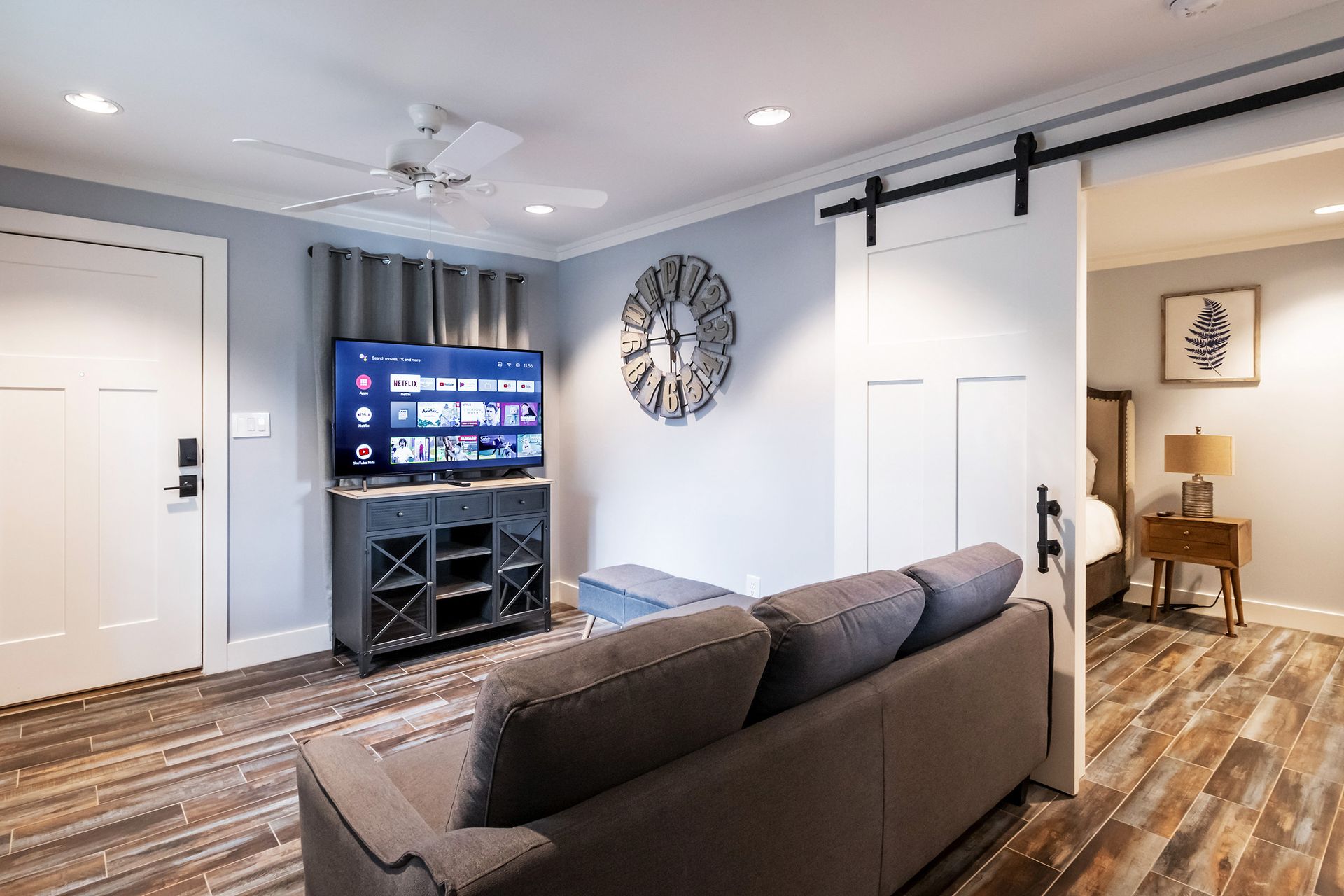 A living room with a couch , television , and sliding barn doors.