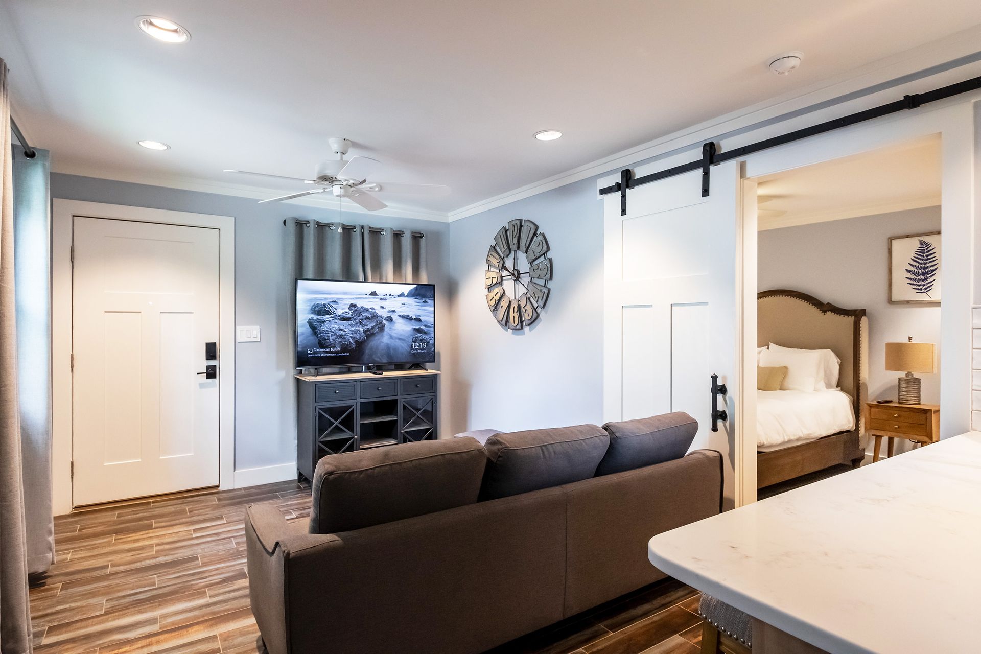 A living room with a couch , television , and sliding barn doors leading to a bedroom.