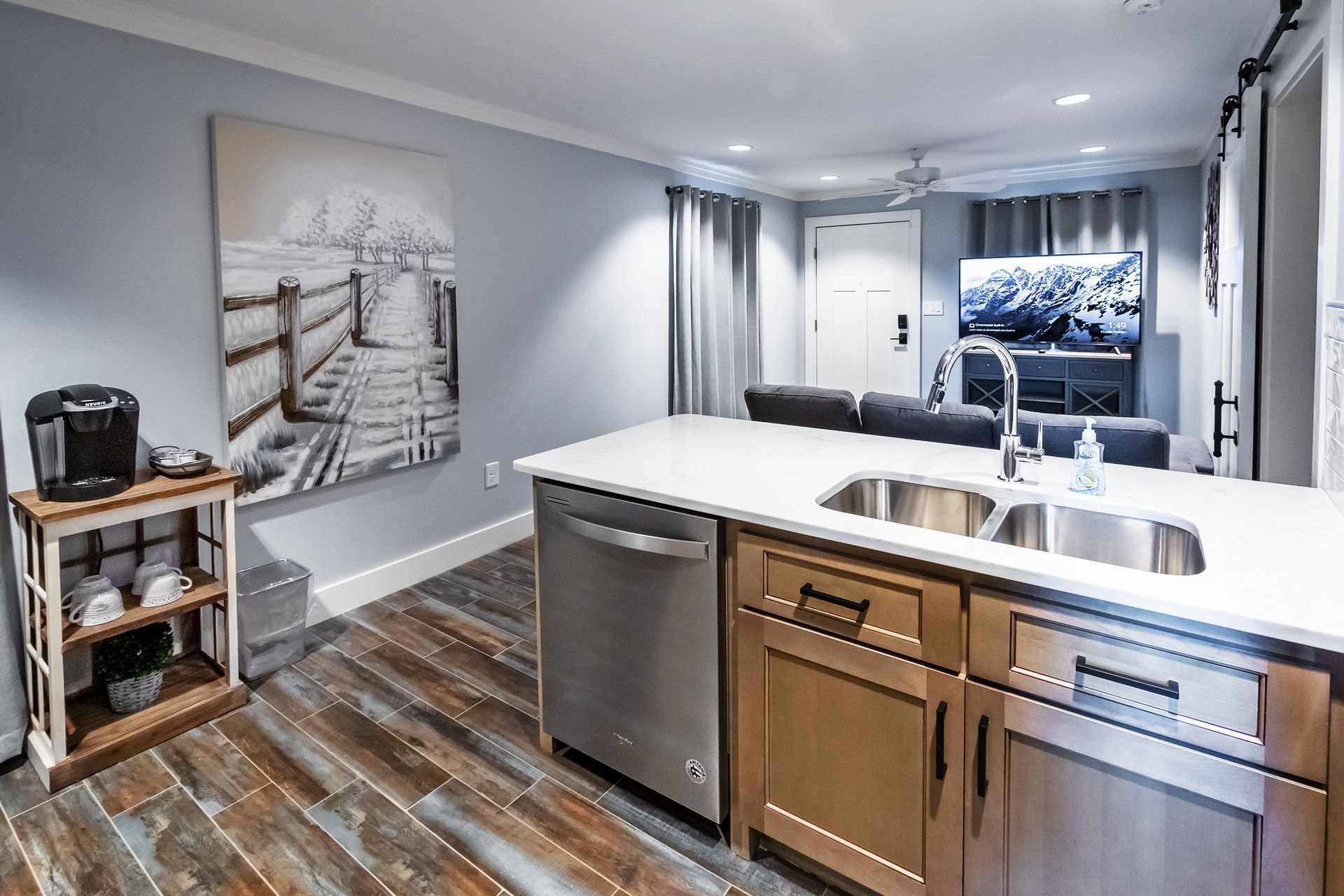 A kitchen with two sinks , a dishwasher , and a painting on the wall.