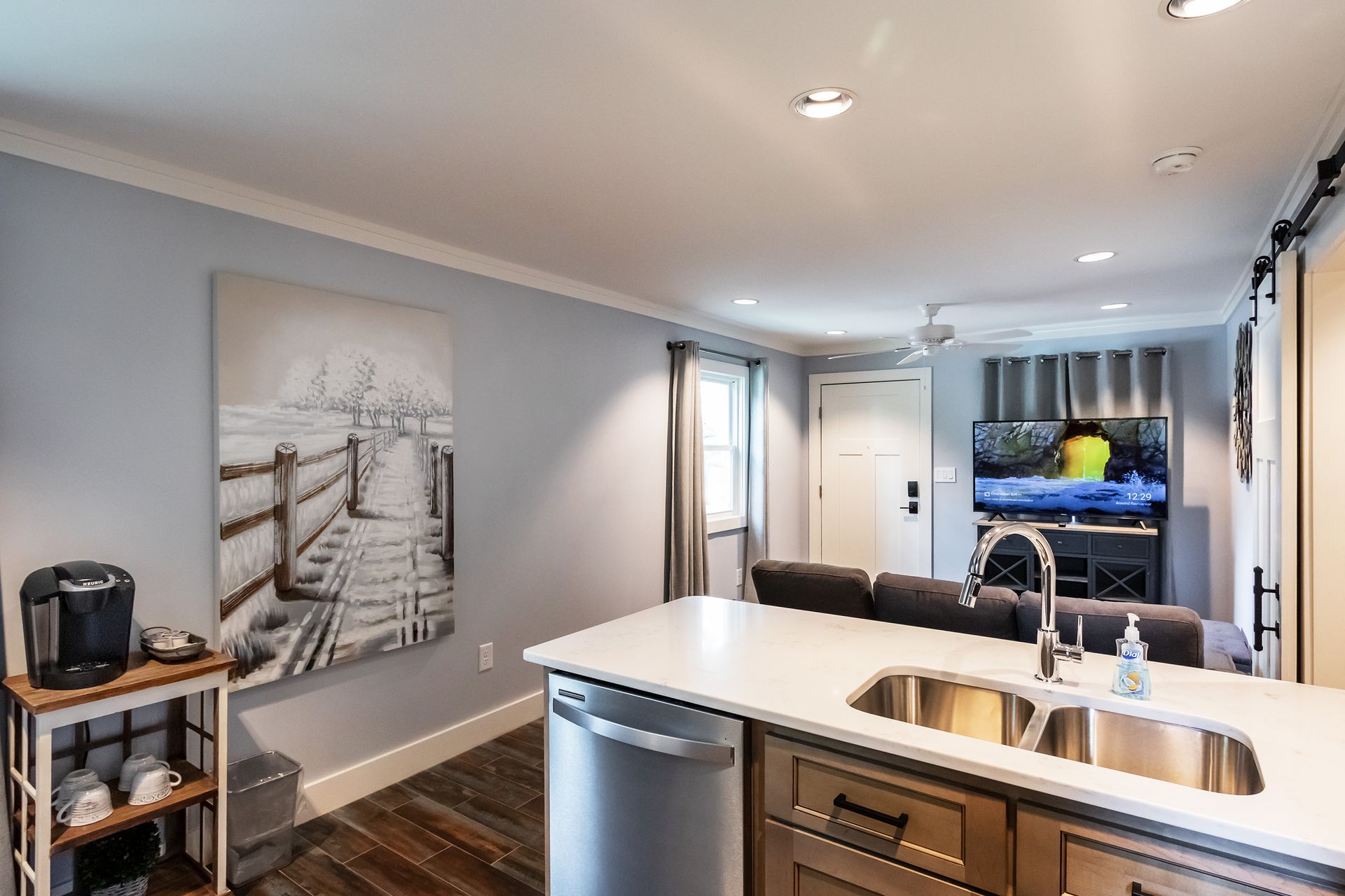 A kitchen with stainless steel appliances and a painting on the wall.