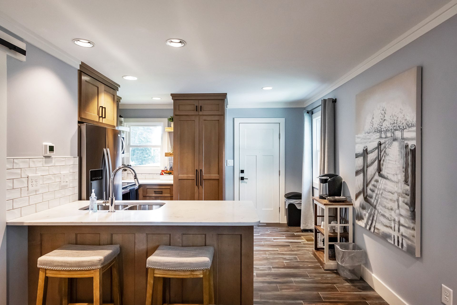 A kitchen with a large island and stools and a painting on the wall.