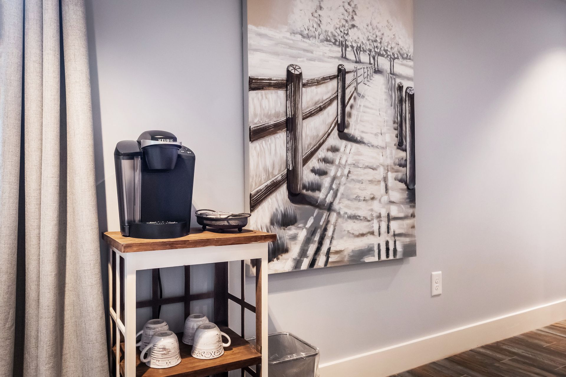 A room with a coffee maker and a painting on the wall.