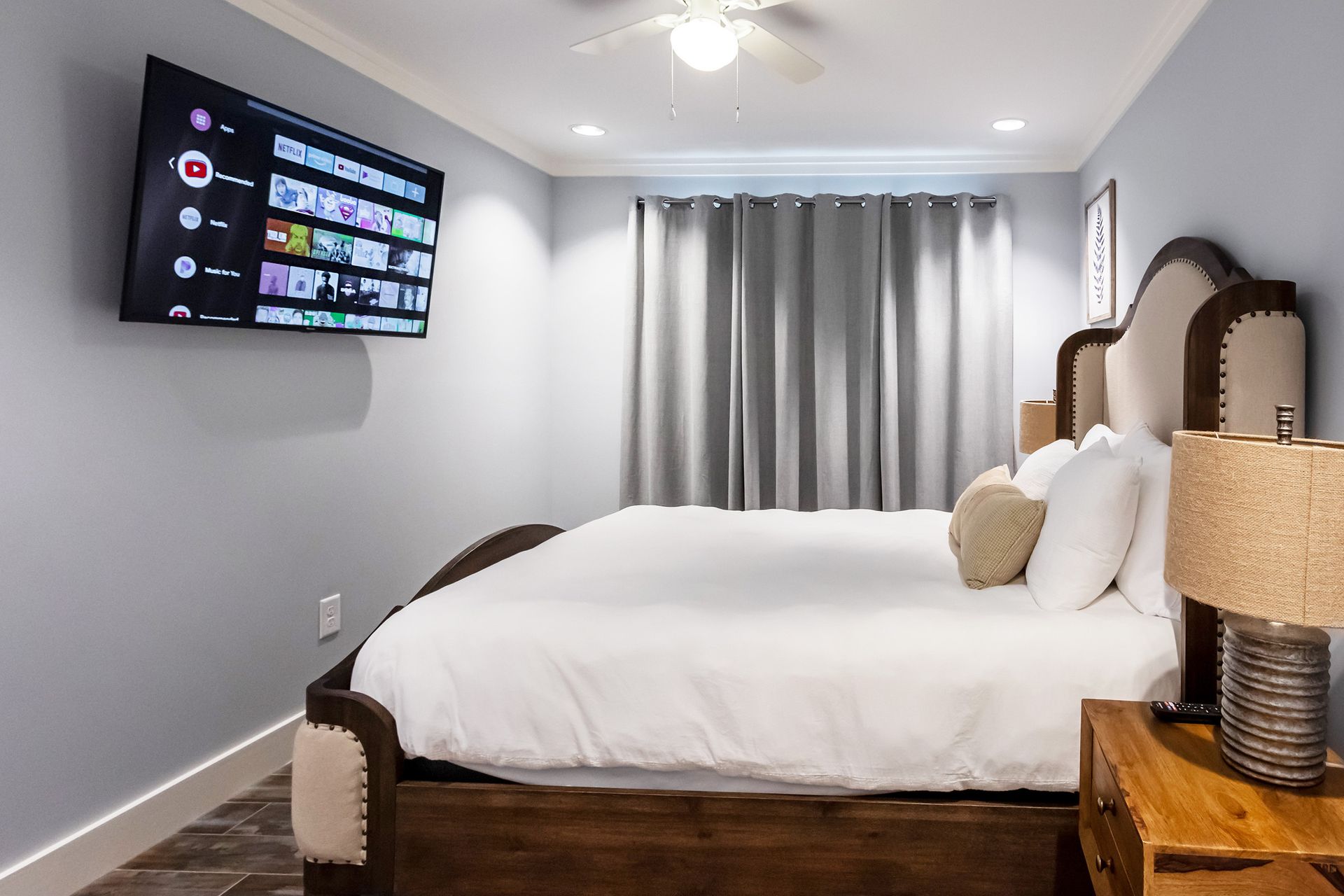 A bedroom with a large bed and a flat screen tv on the wall.
