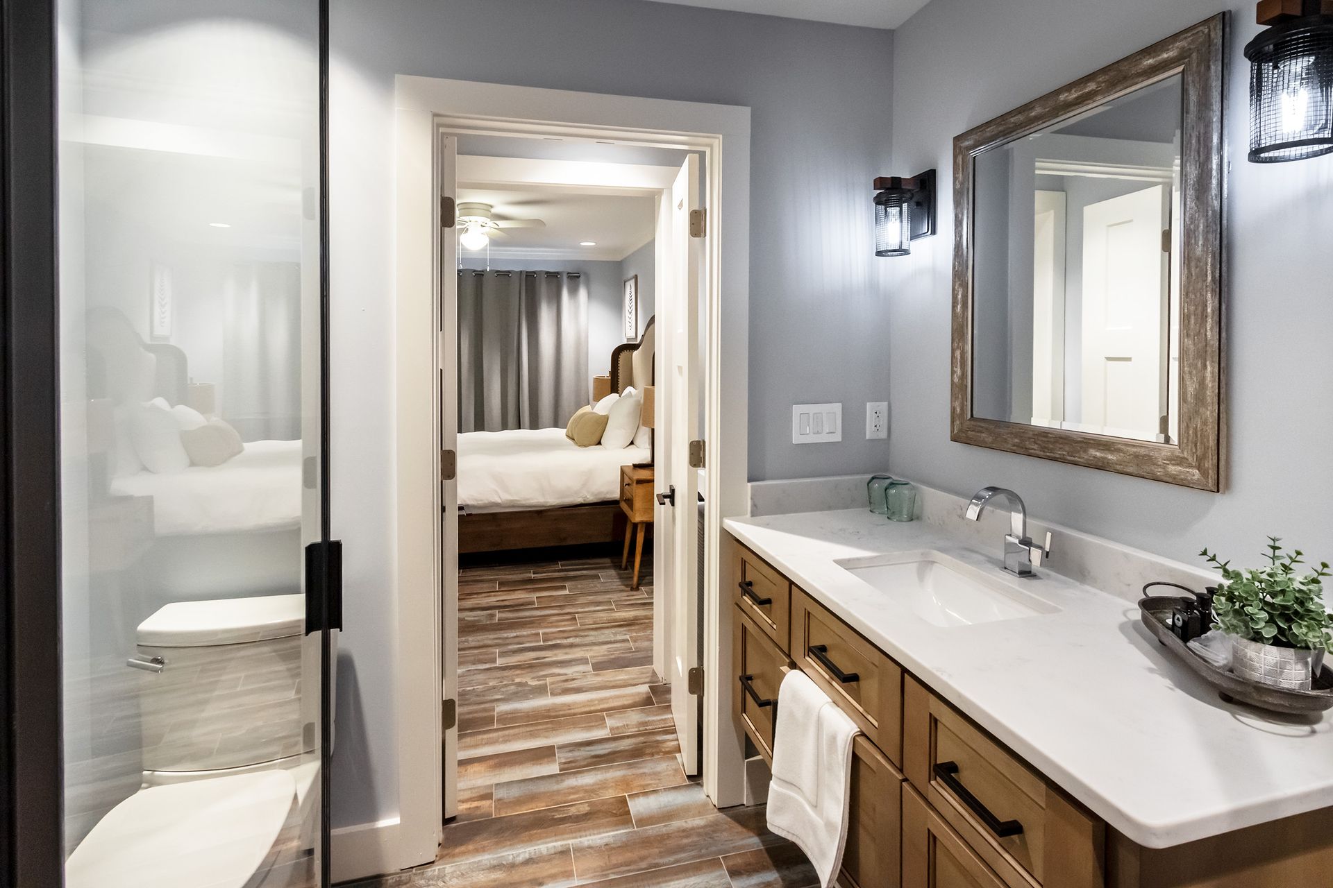 A bathroom with a sink , toilet , mirror and walk in shower.