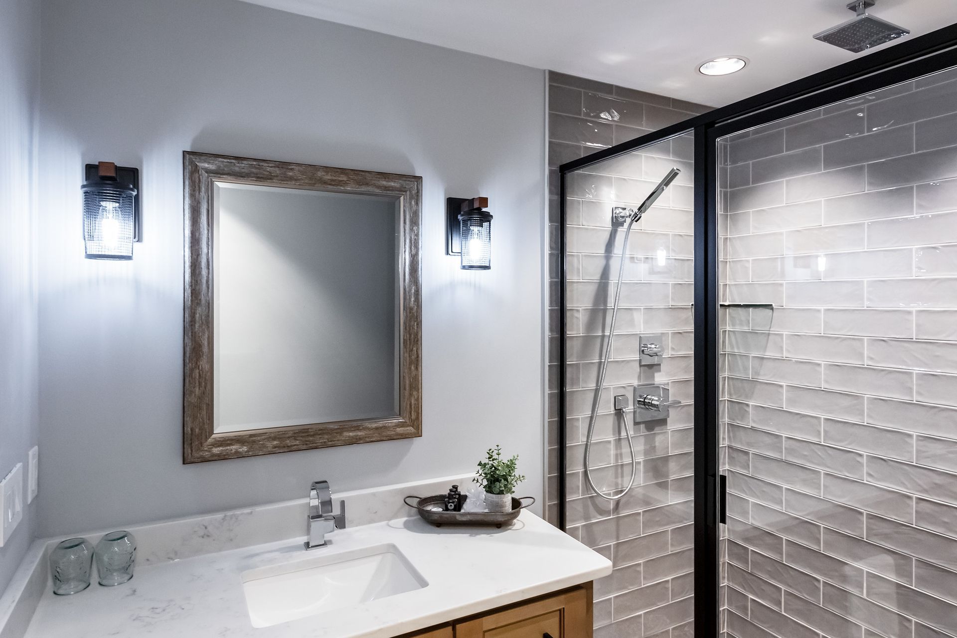 A bathroom with a sink , mirror and shower.