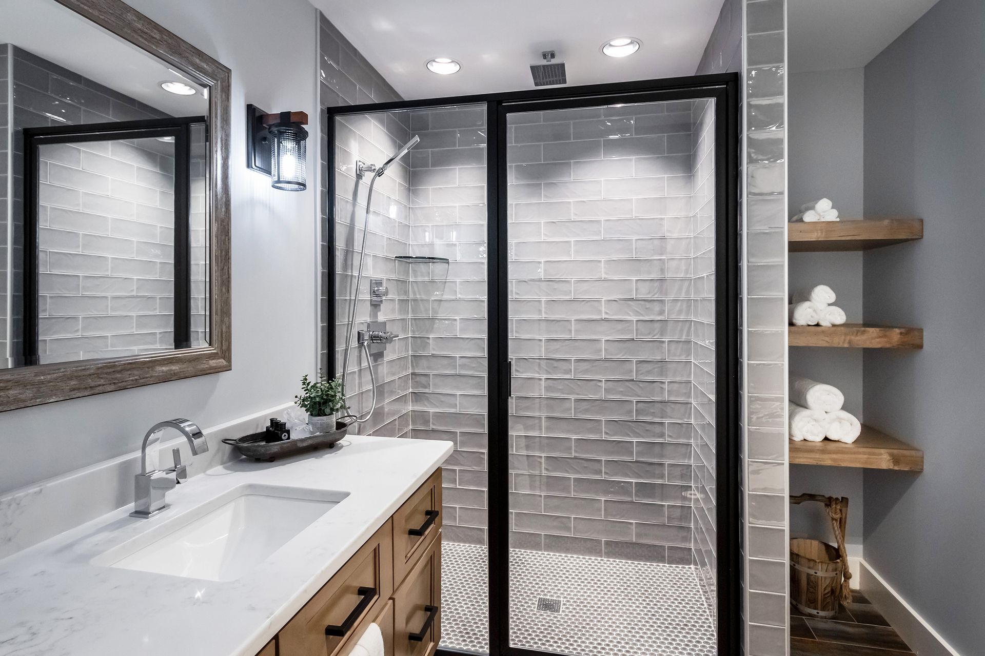 A bathroom with a sink , mirror and walk in shower.