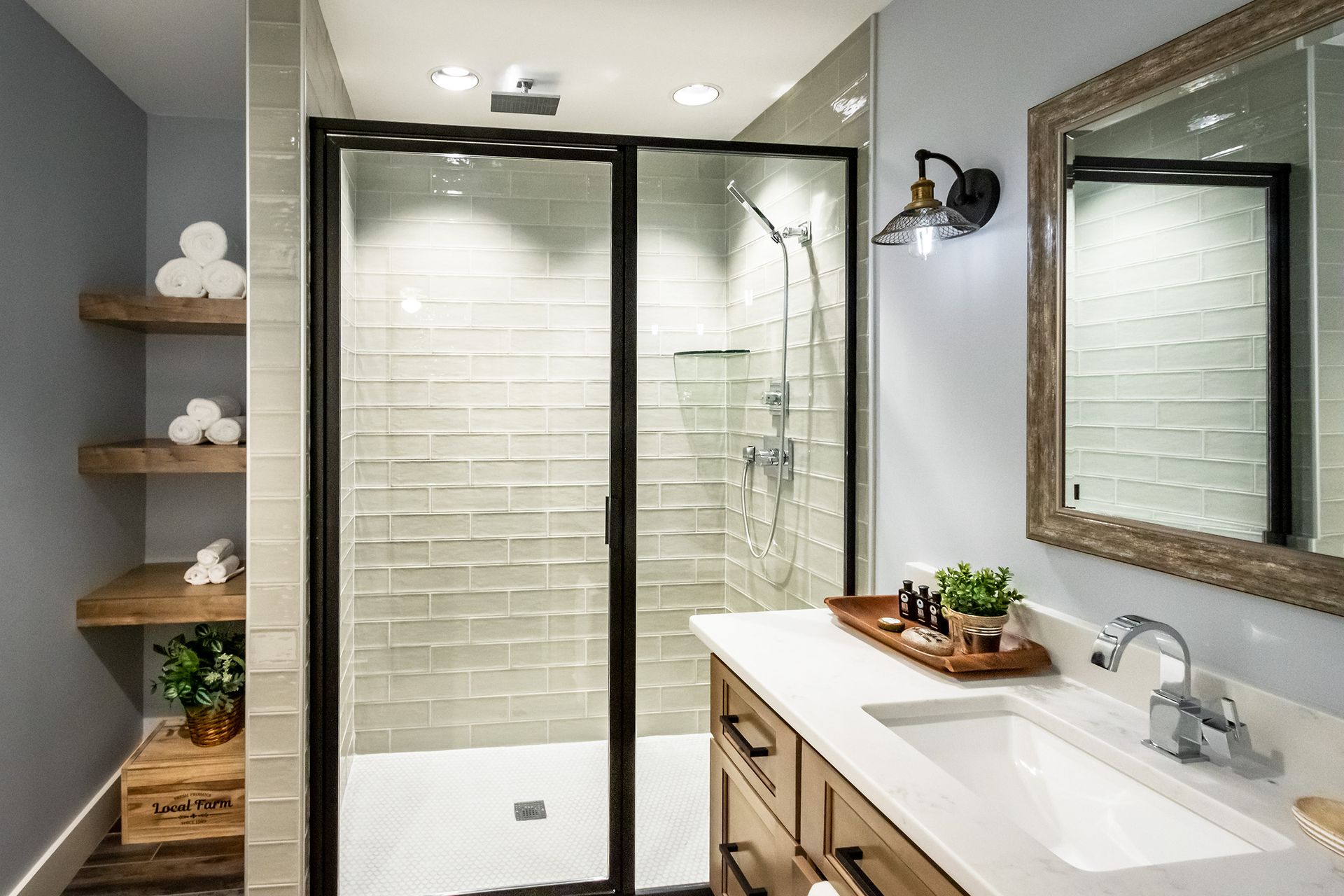 A bathroom with a sink , mirror and walk in shower.
