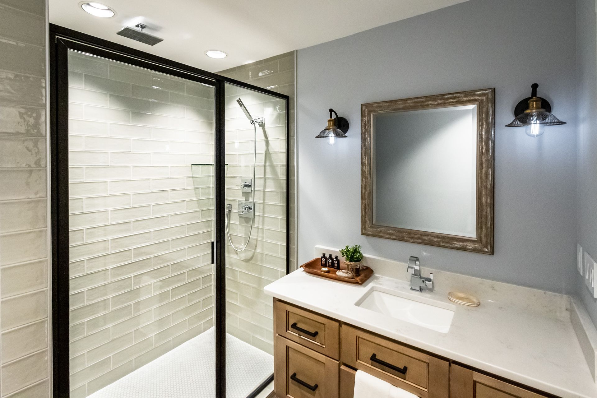 A bathroom with a sink , mirror and walk in shower.