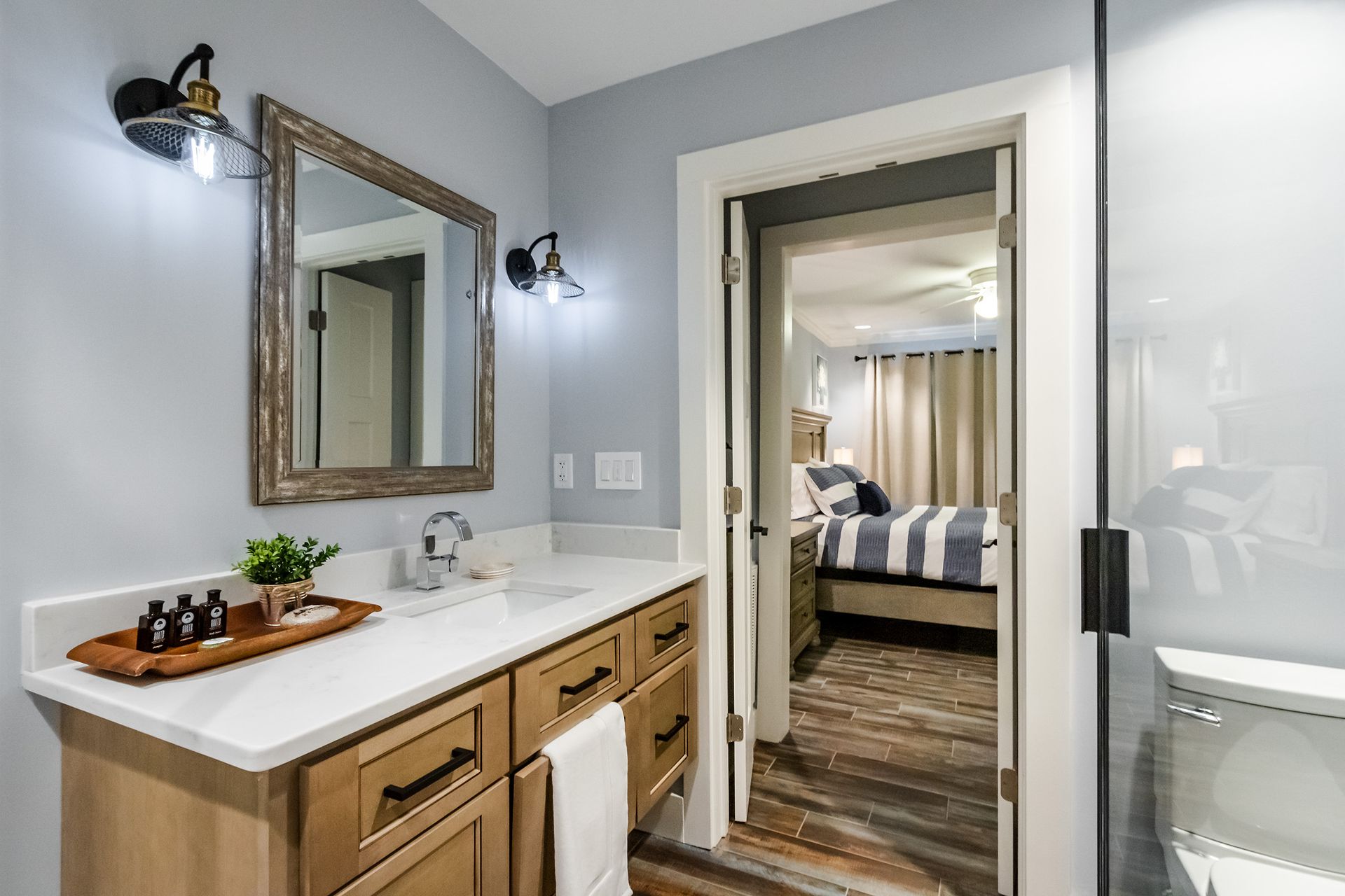 A bathroom with a sink , mirror , toilet and walk in shower.
