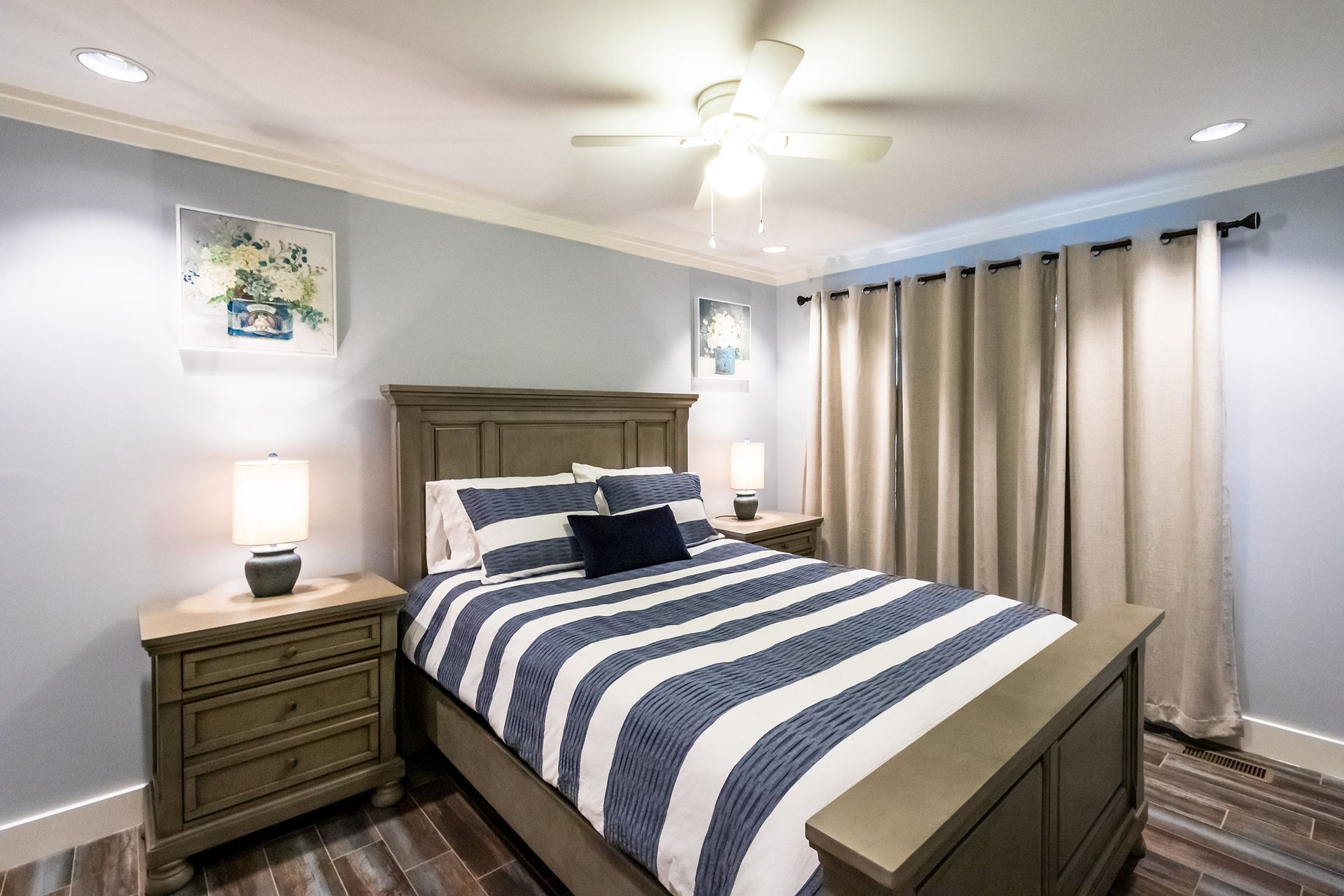 A bedroom with a bed , nightstand , dresser and ceiling fan.