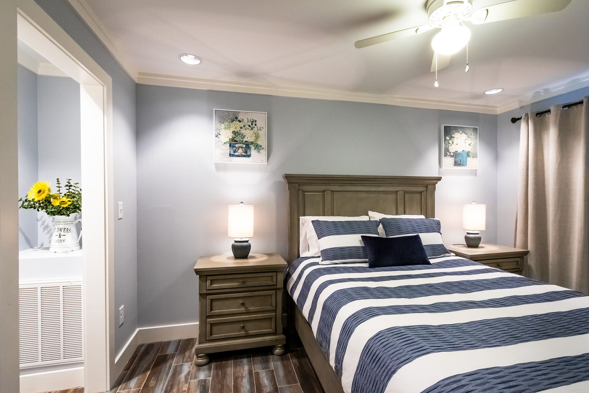 A bedroom with a bed , nightstand , lamps and a ceiling fan.