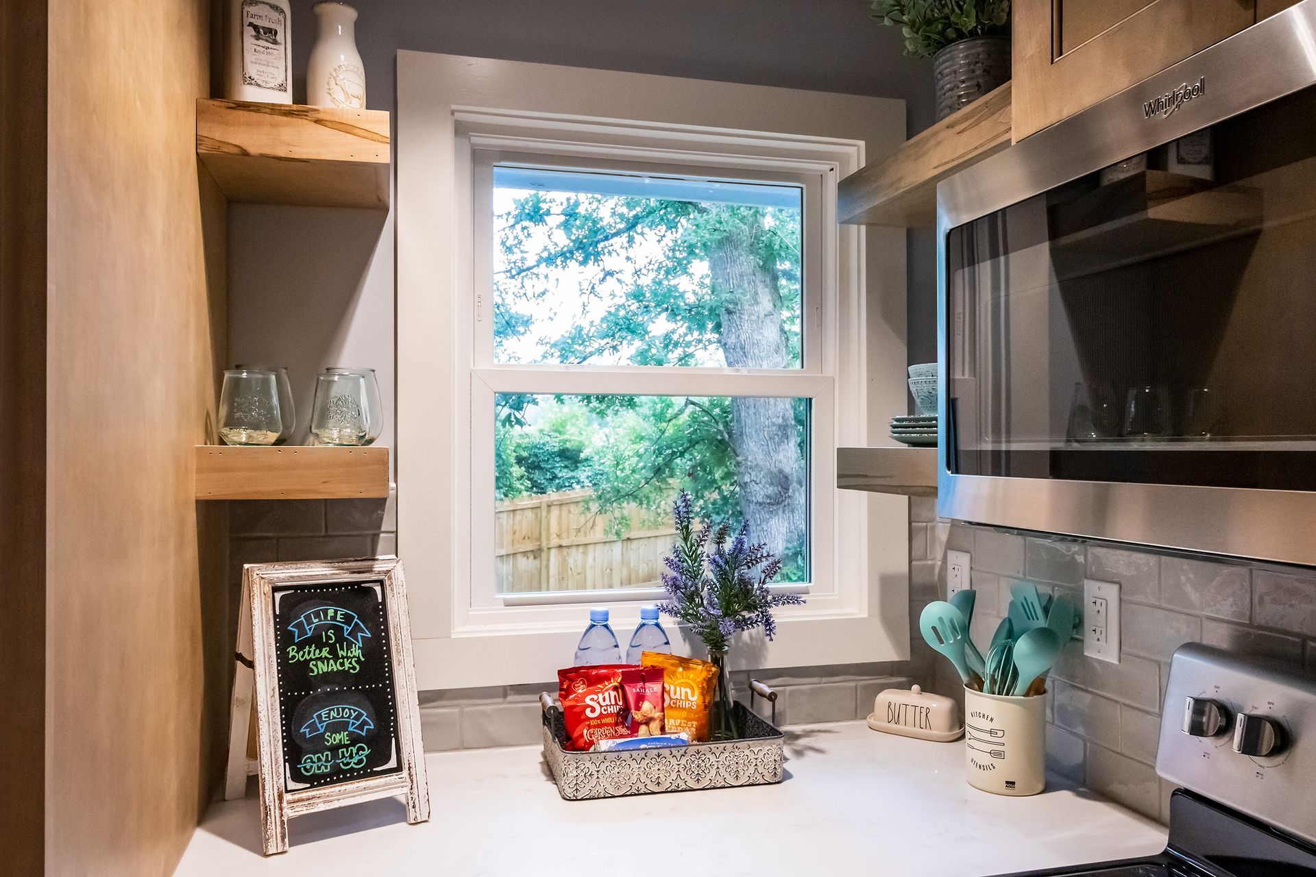 A kitchen with a stove , microwave , and window.