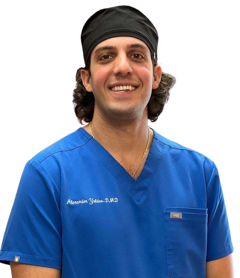 A man wearing a blue scrub top and a black headband is smiling.