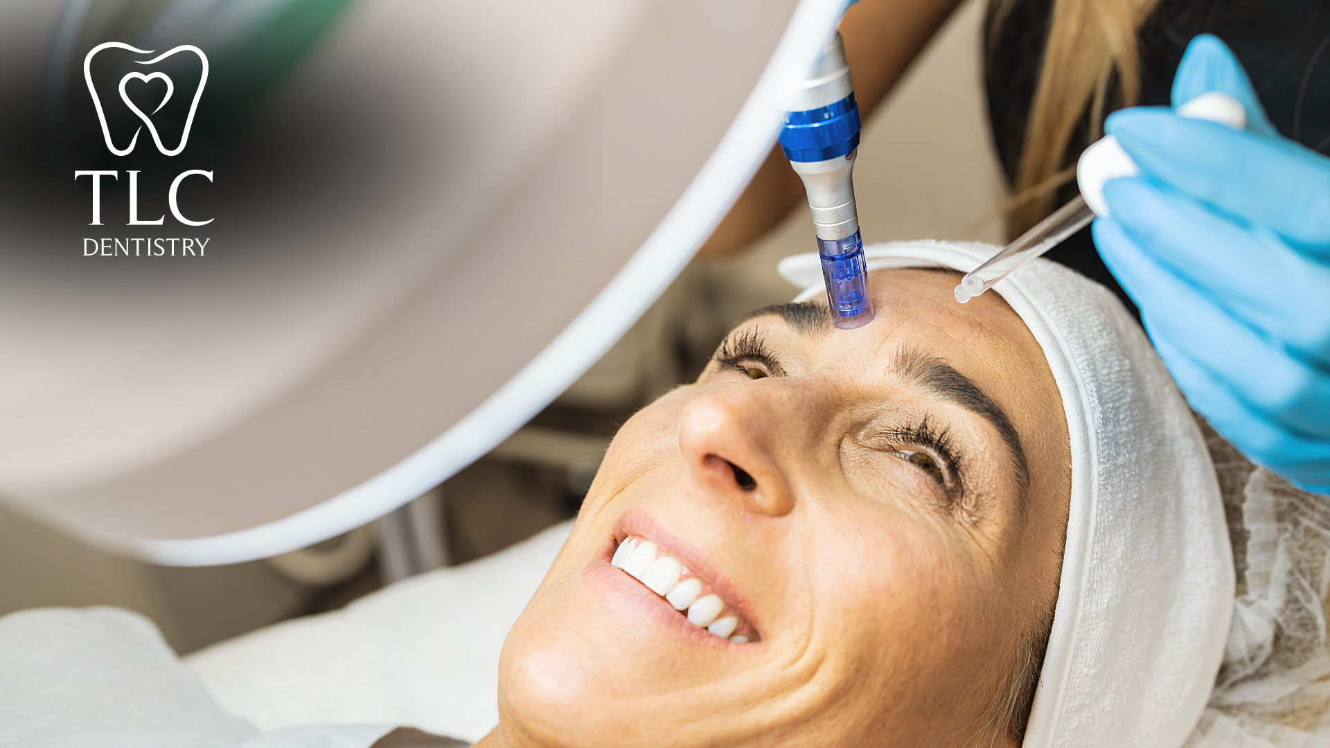 A woman is smiling while getting a treatment on her forehead.