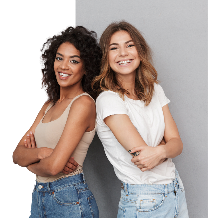 Two women are standing back to back with their arms crossed and smiling.