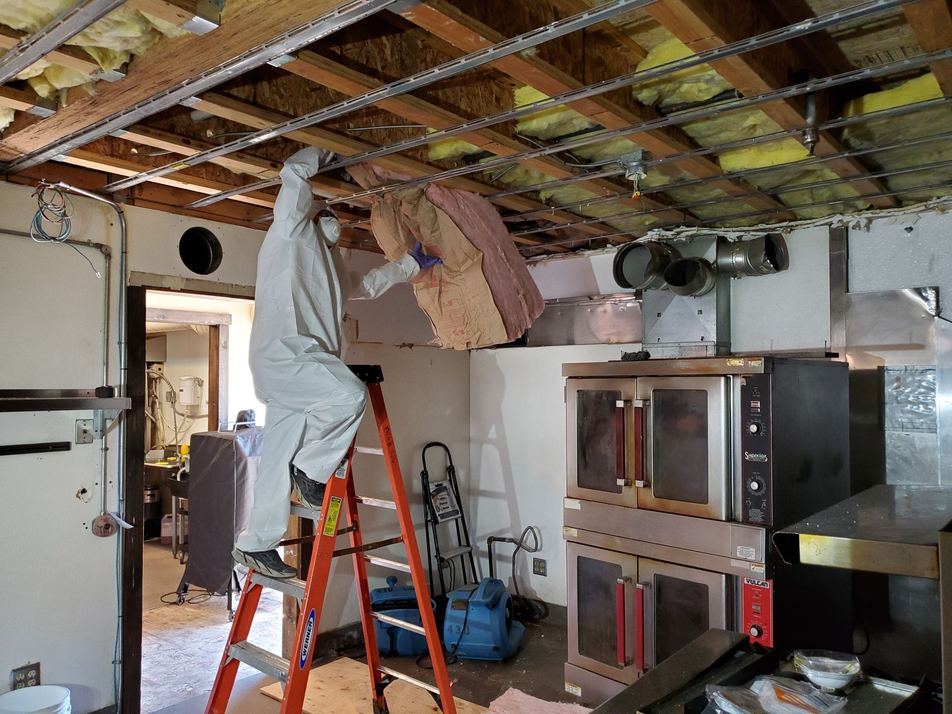 A man is standing on a ladder in a kitchen.