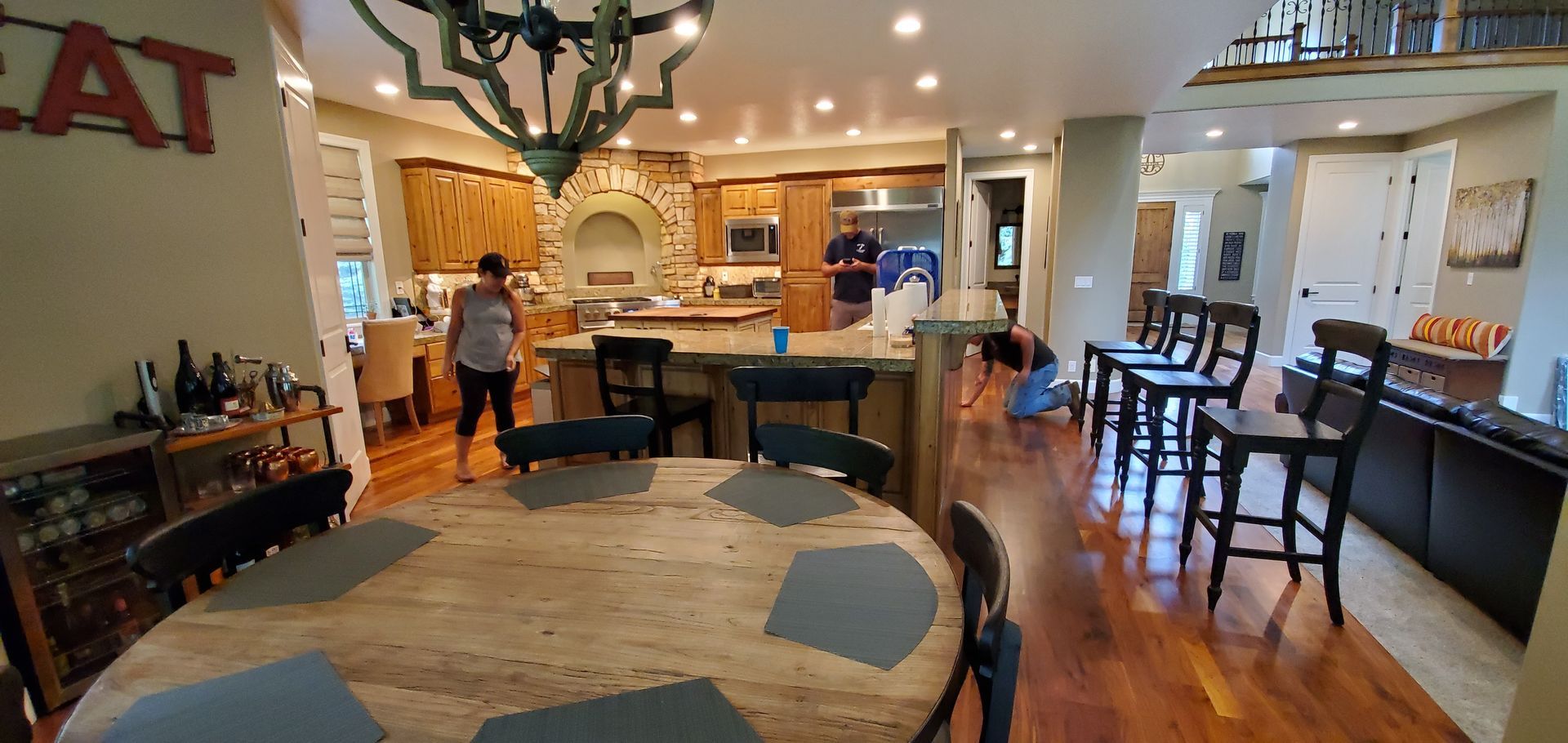 A woman is standing in a kitchen next to a dining room table.