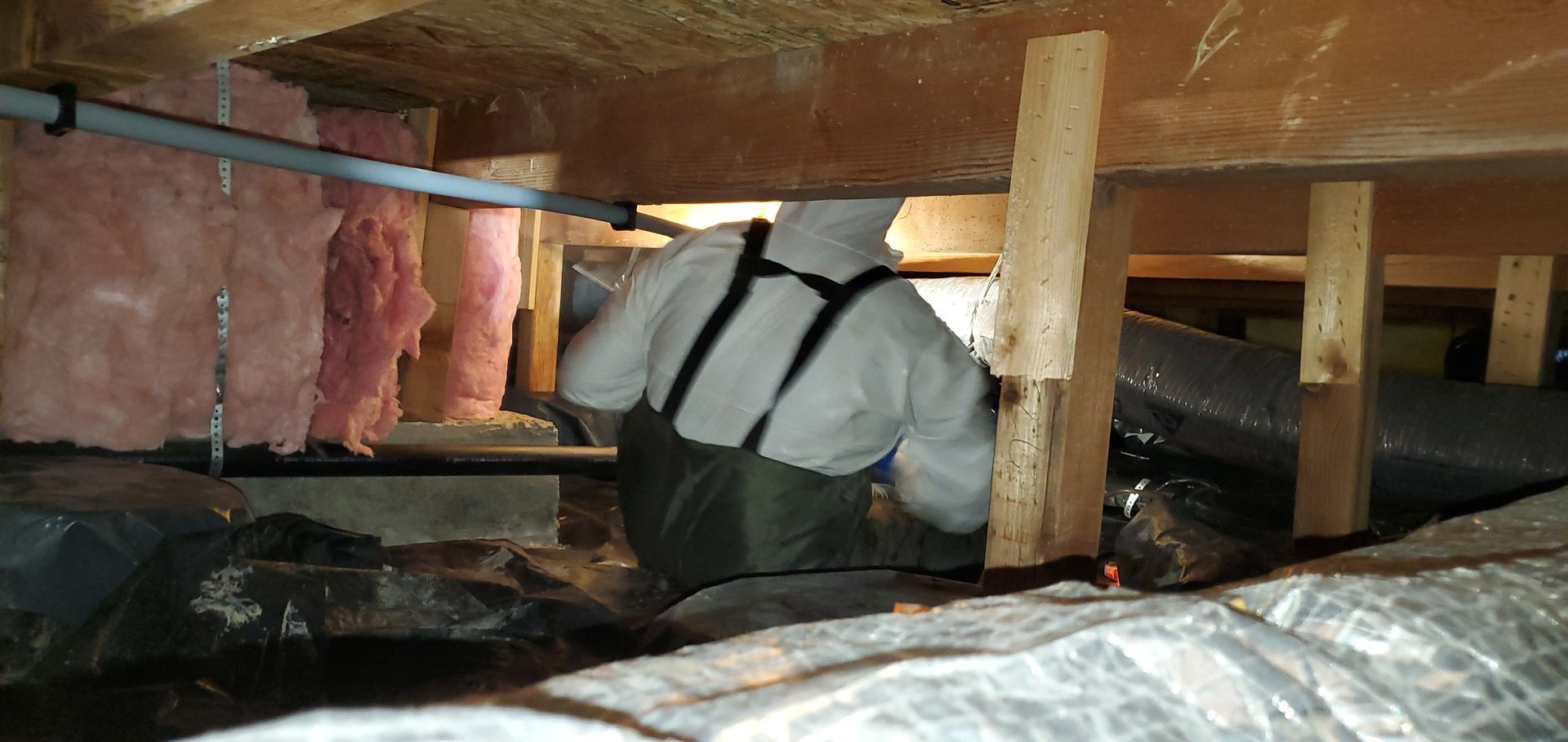 A man is standing in the crawl space of a house.