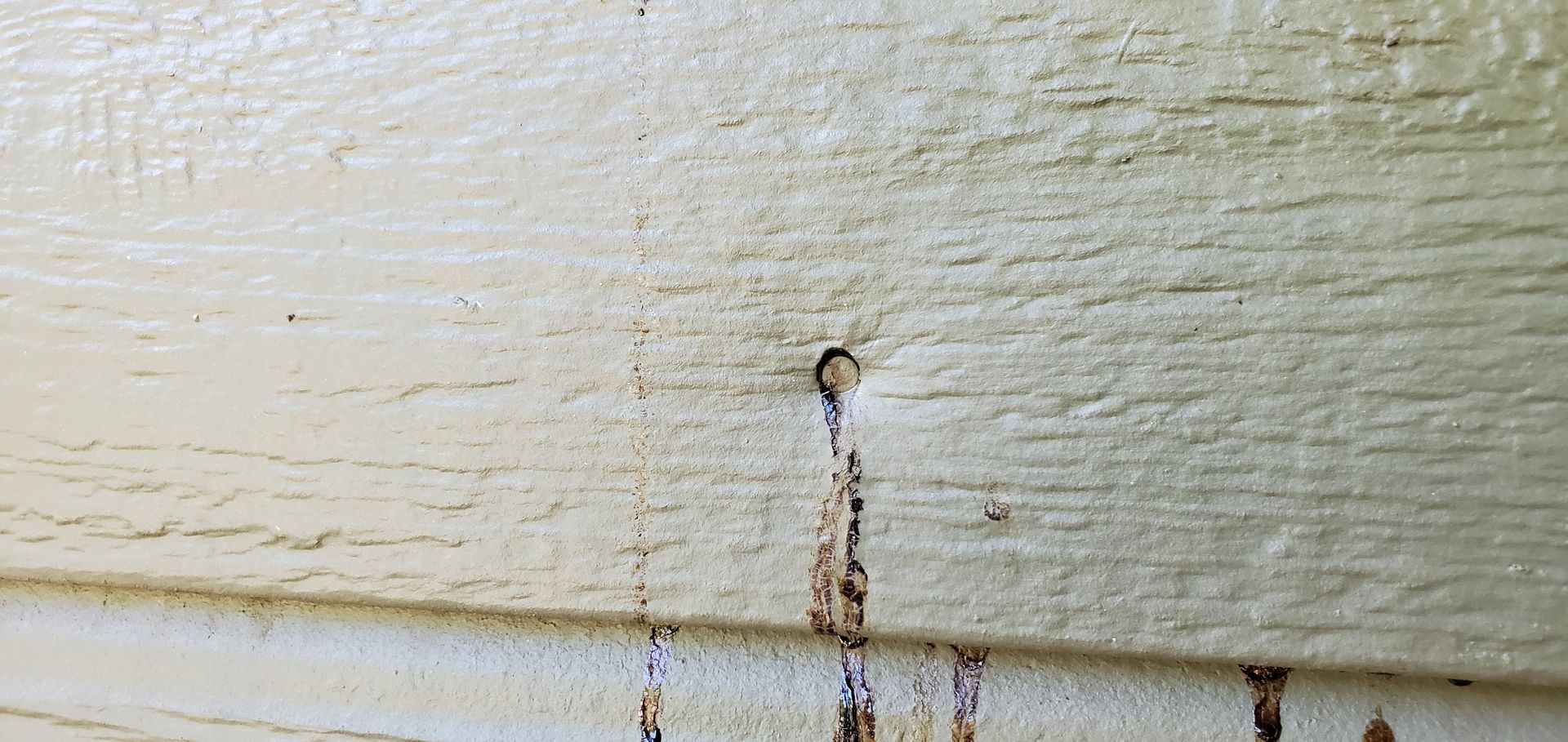 A close up of a white wooden wall with a hole in it.