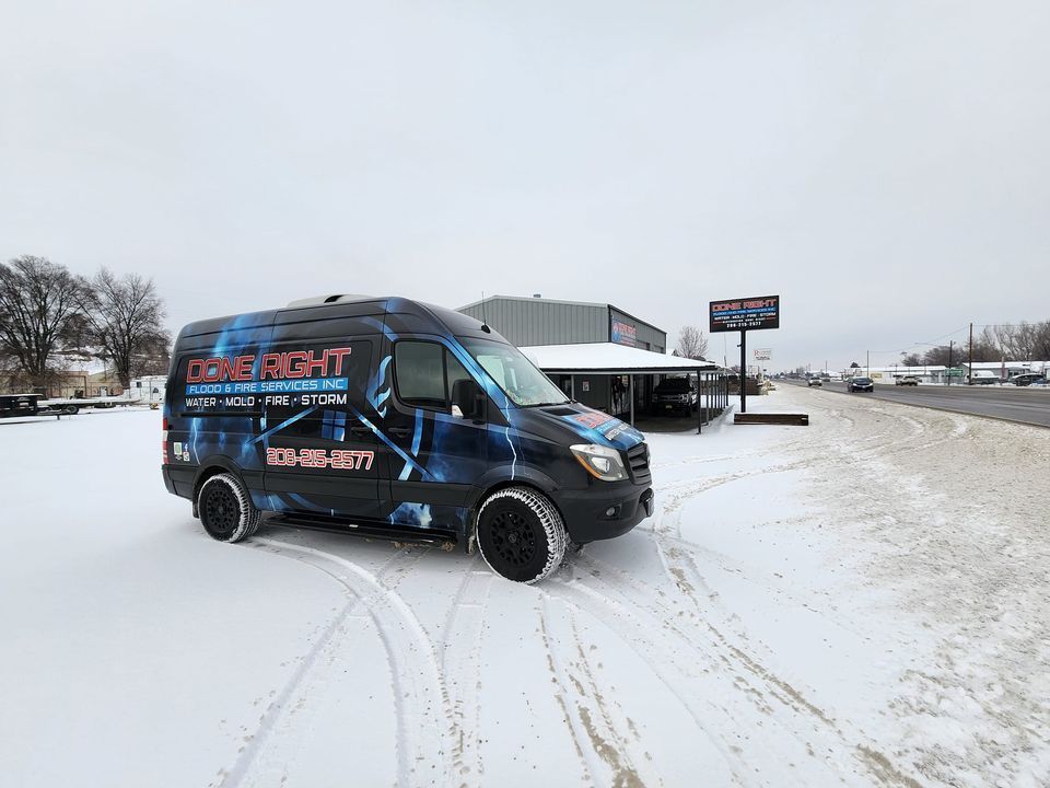 A van is parked in the snow in front of a building.