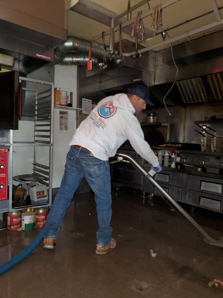 A man is using a vacuum cleaner in a kitchen