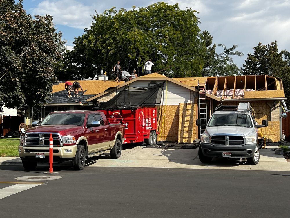 Two trucks are parked in front of a house under construction.
