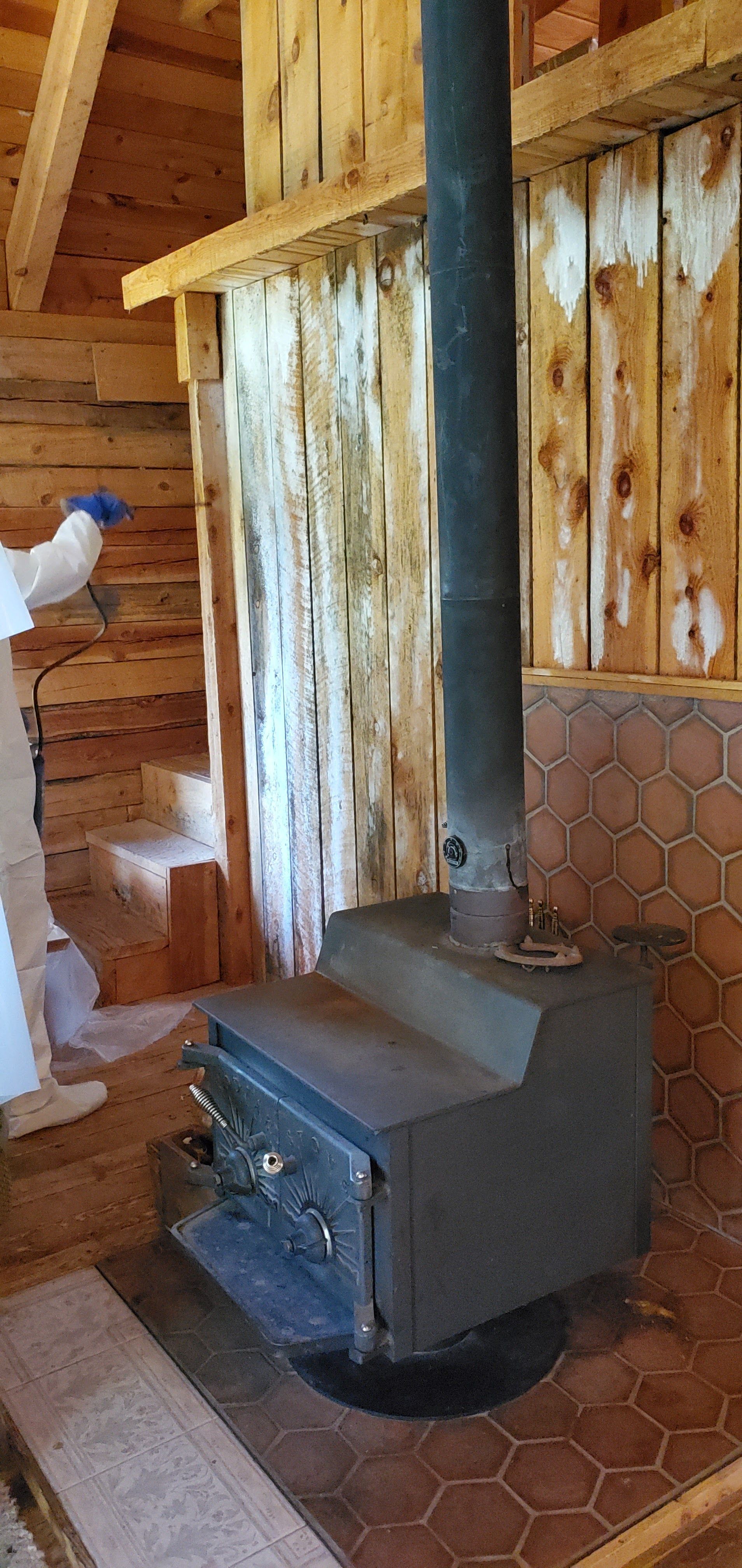 A wood stove is sitting in a wooden room next to a wooden wall.