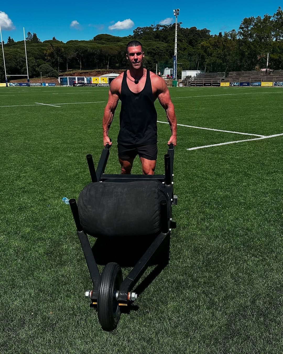 Jay Gardner is pushing a wheelbarrow on a field