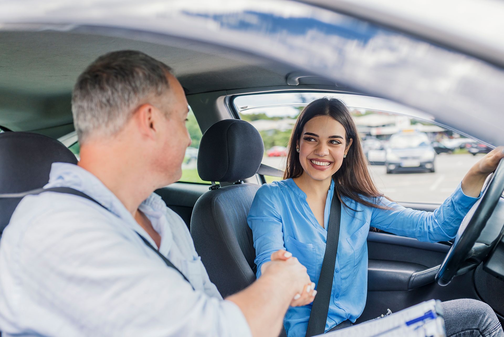 A man is teaching a woman how to drive a car.